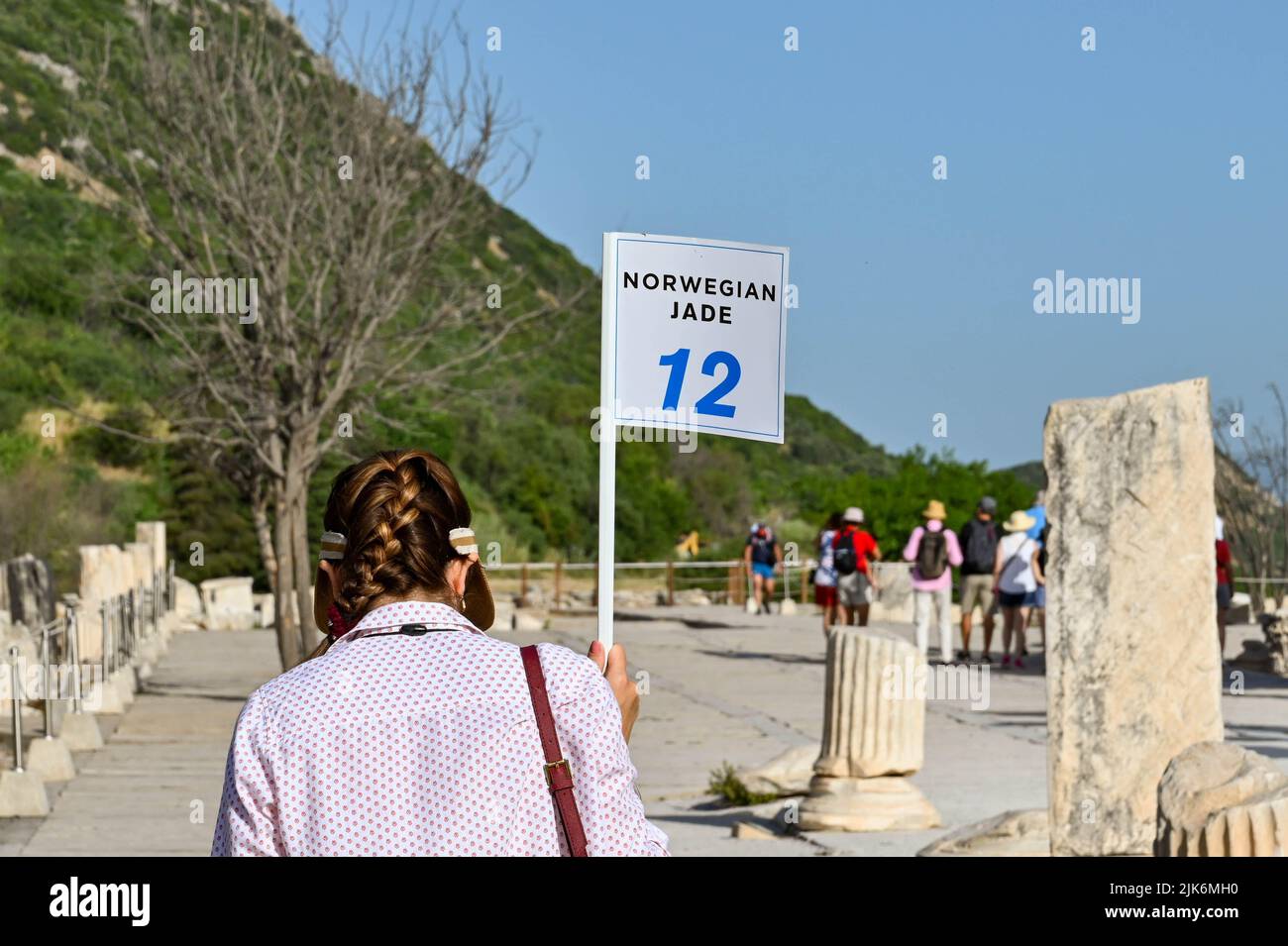Ephesus, Kusadasi, Turkey - May 2022: Tour guide holding up a flag for her tour group to follow through the ruins of the ancient city of the Roman Emp Stock Photo