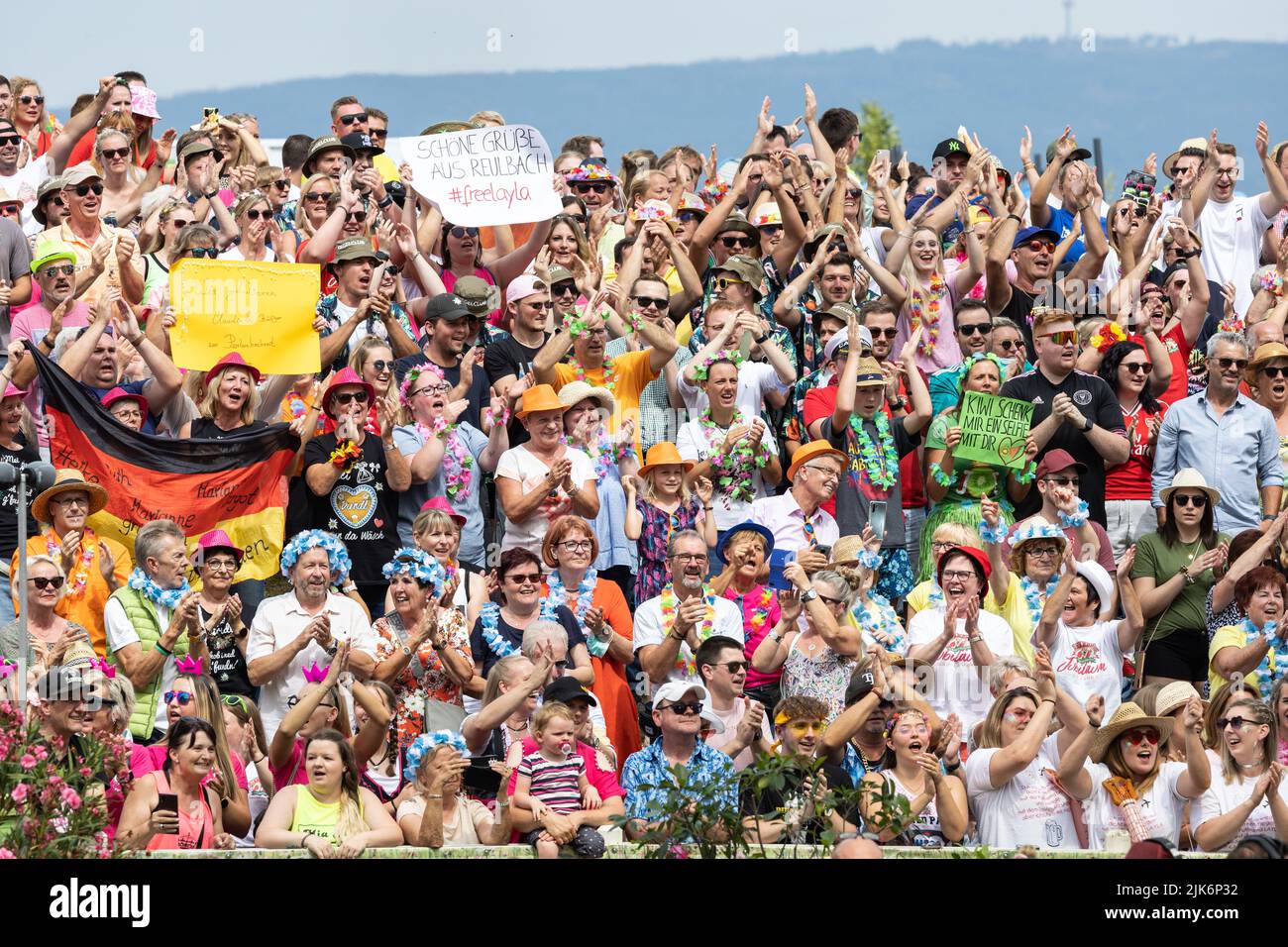 Mainz, Germany. 31st July, 2022. The audience celebrates during the live show 'ZDF-Fernsehgarten' - a sign with the inscription 'Schöne Grüße aus Reulbach #freelayla' can also be seen. For weeks, there has been a sexism debate about the controversial song 'Layla' by the duo DJ Robin & Schürze. On Sunday, 'Fernsehgarten' had the party motto 'Mallorca vs. Oktoberfest. Credit: Hannes P. Albert/dpa/Alamy Live News Stock Photo