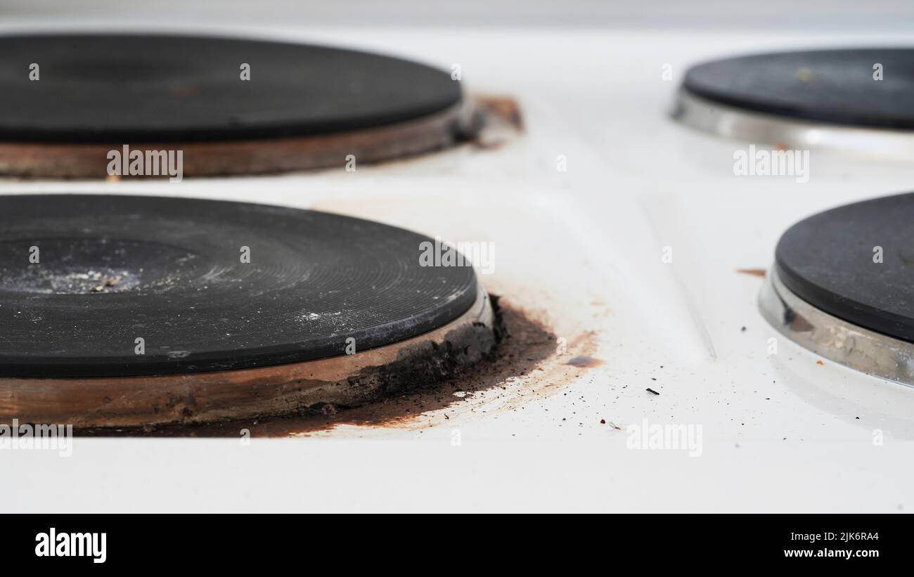 Close-up of a dirty stove with leftover food. Dirty gas stove with grease stains, old grease stains, fried stains and oil splashes.Macro photo.Texture Stock Photo