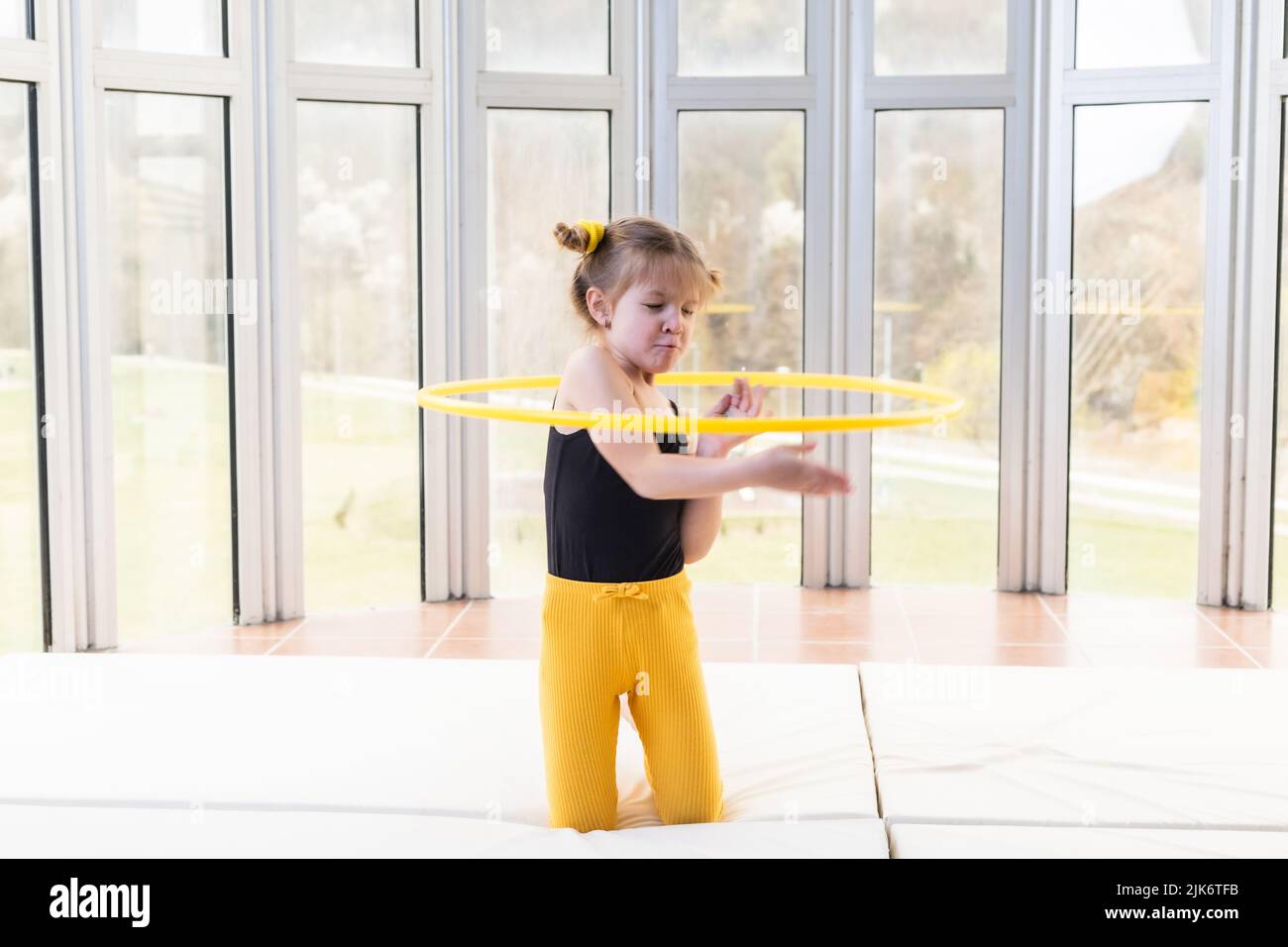 Little blonde girl with piggy tails playing with hula hoop Stock Photo
