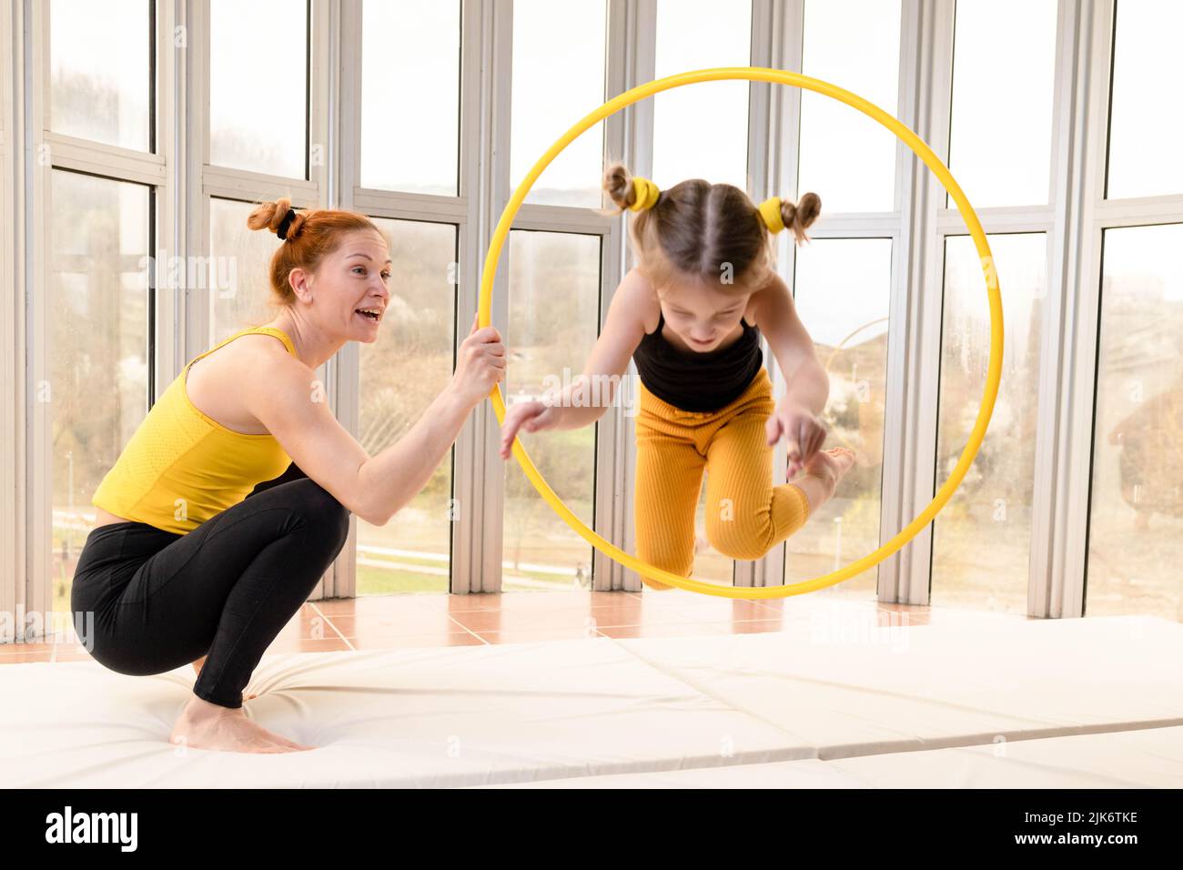 Young fit mom and her daughter having fun with hula hoop in a gym Stock Photo Alamy