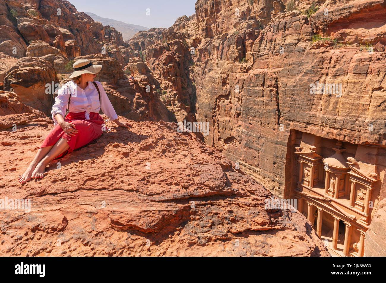young tourist with hat and fashion dress  at Al-Khazneh (The Treasury) one of the most elaborate temples in the ancient city of Petra, Jordan. View fr Stock Photo