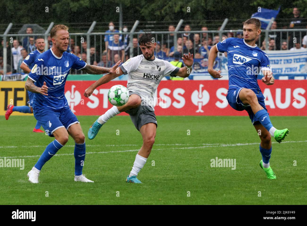 Rodinghausen, Germany. 31st July, 2022. 31 July 2022, North Rhine-Westphalia, Rödinghausen: Soccer: DFB Cup, SV Rödinghausen - TSG 1899 Hoffenheim, 1st round, Häcker-Wiehenstadion. Rödinghausen's Vincent Schaub (center) battles for the ball with Hoffenheim's Kevin Vogt (left) and Stefan Posch (right). Photo: Friso Gentsch/dpa - IMPORTANT NOTE: In accordance with the requirements of the DFL Deutsche Fußball Liga and the DFB Deutscher Fußball-Bund, it is prohibited to use or have used photographs taken in the stadium and/or of the match in the form of sequence pictures and/or video-like photo se Stock Photo