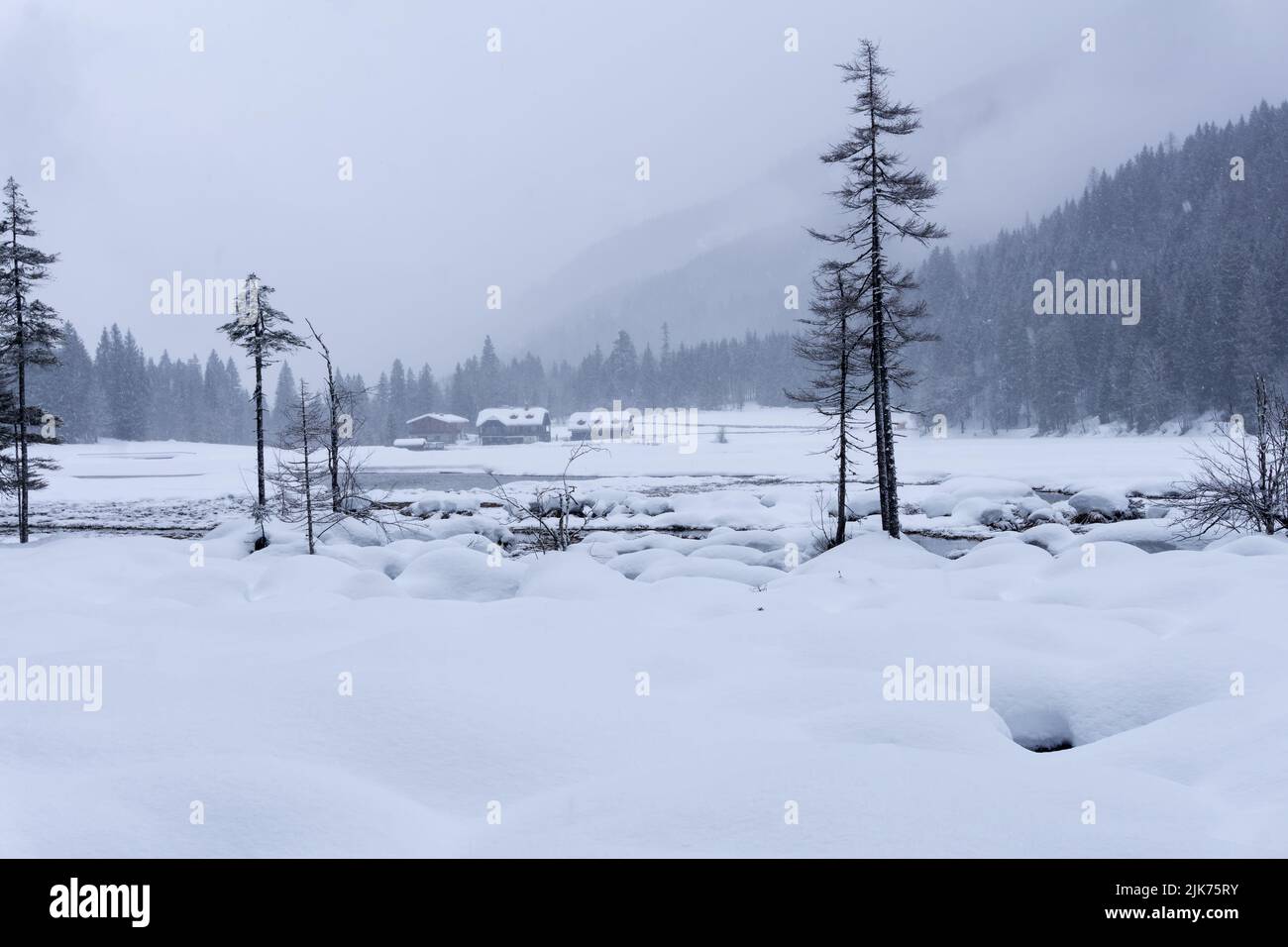 Winter landscape with frozen lake and snowfall.  Sorrounded mountains covered in the fog. Jagersee, Salzburger Alps, Austria, Europe. Stock Photo