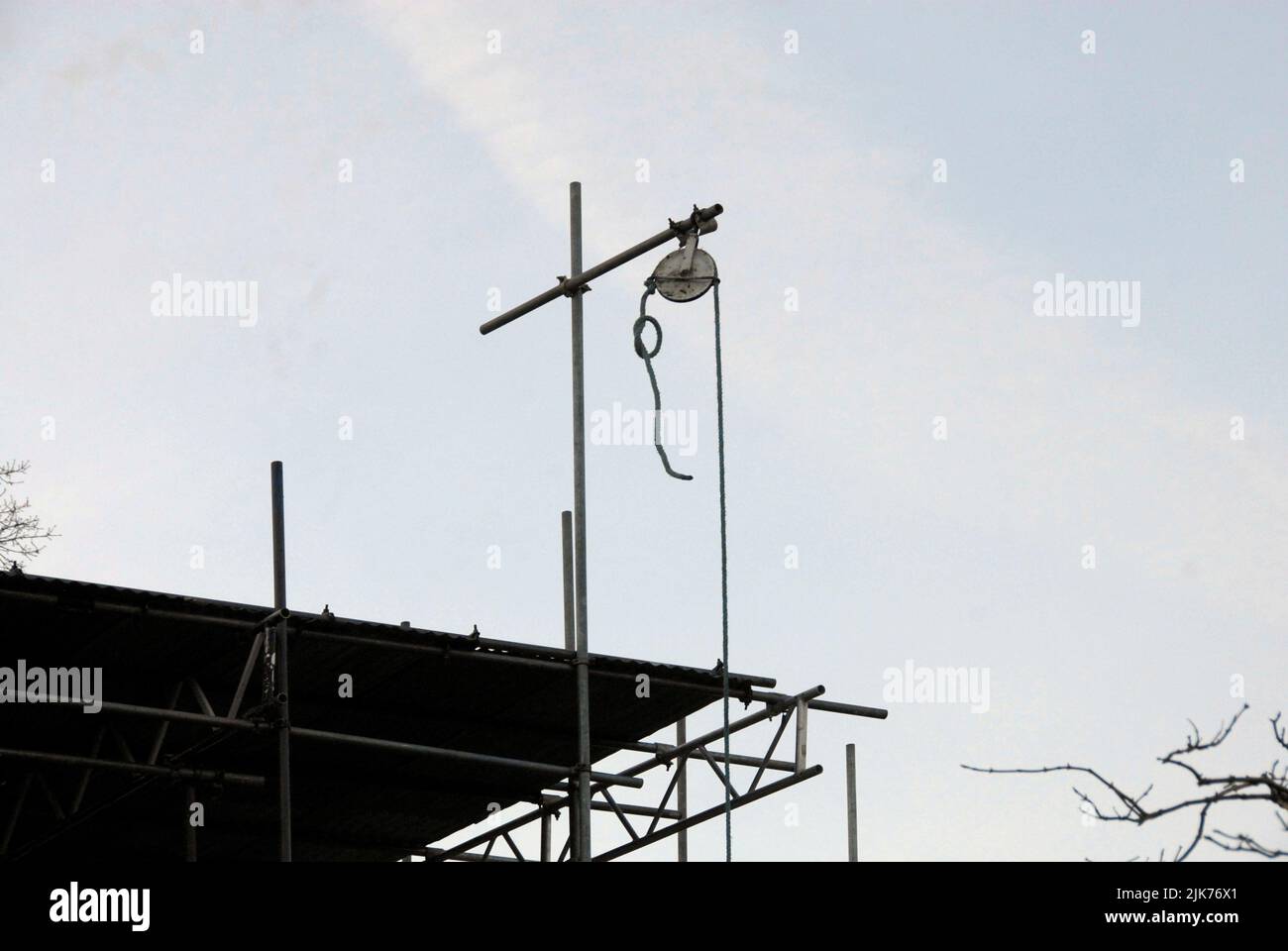 Pulley on scaffolding above new house construction to enable material to be raised and lowered  more easily, with knot tied in rope to prevent loss Stock Photo