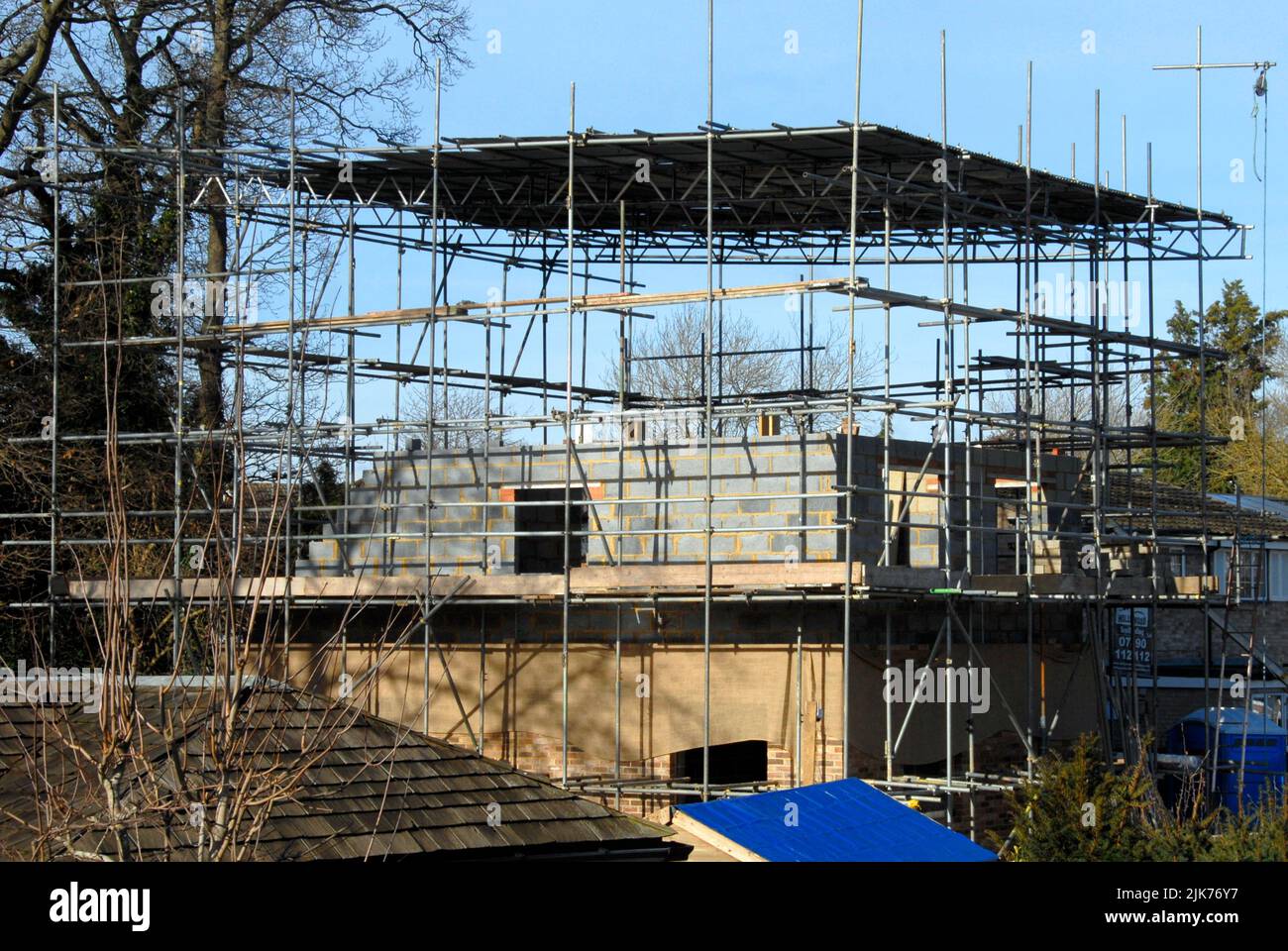 Scaffolding covered with corrugated iron sheeting above a new house being built to provide temporary protection against possible inclement weather Stock Photo