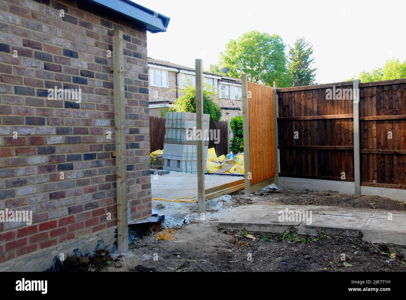 Partially completed fence between two houses using different materials Stock Photo