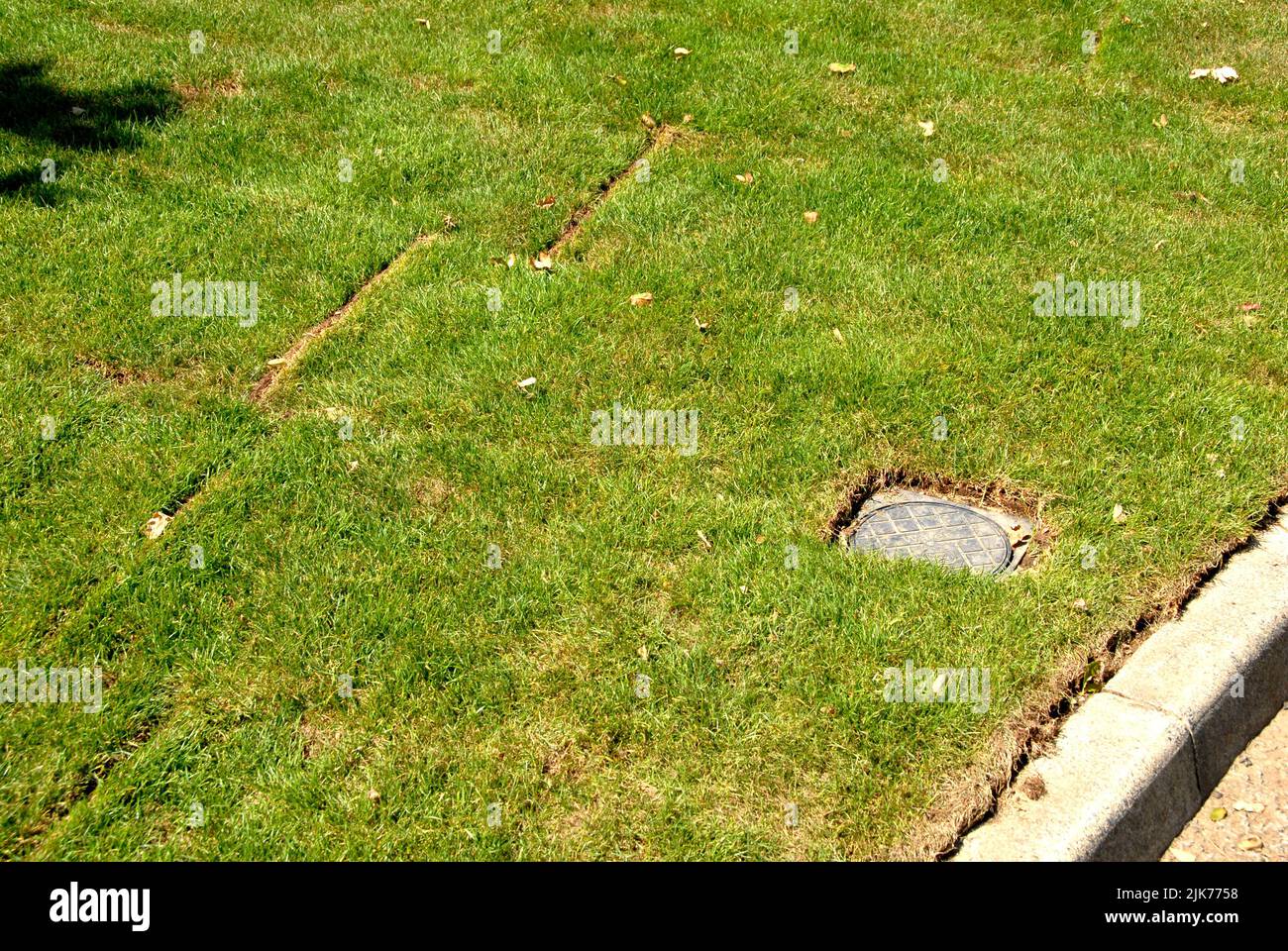 Freshly laid turfs at roadside with hole cut for access to water meter Stock Photo