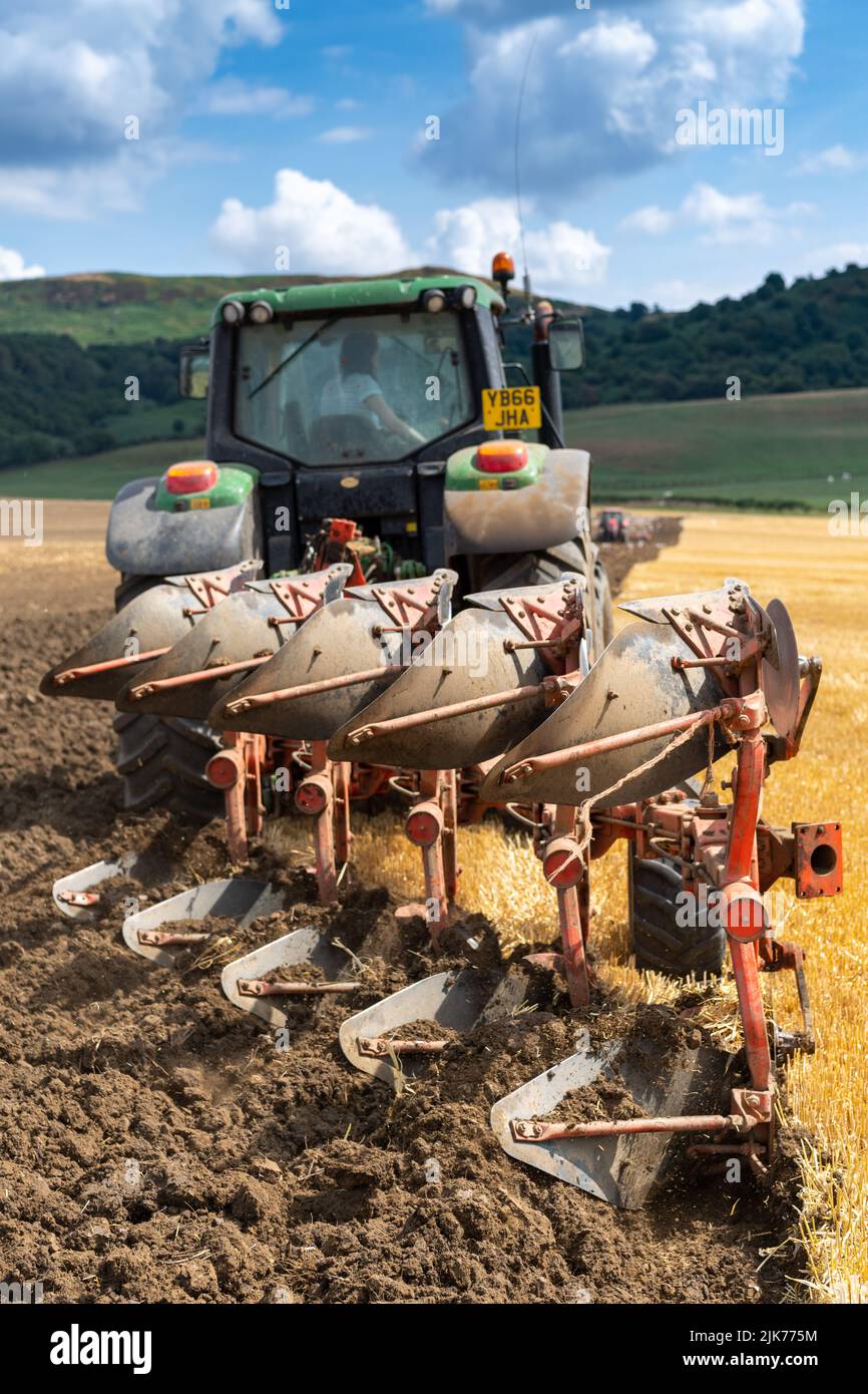 Ploughing in stubble on an arable field with a John Deere 6155M tractor and a 5 furrow reversible plough. North Yorkshire, UK. Stock Photo