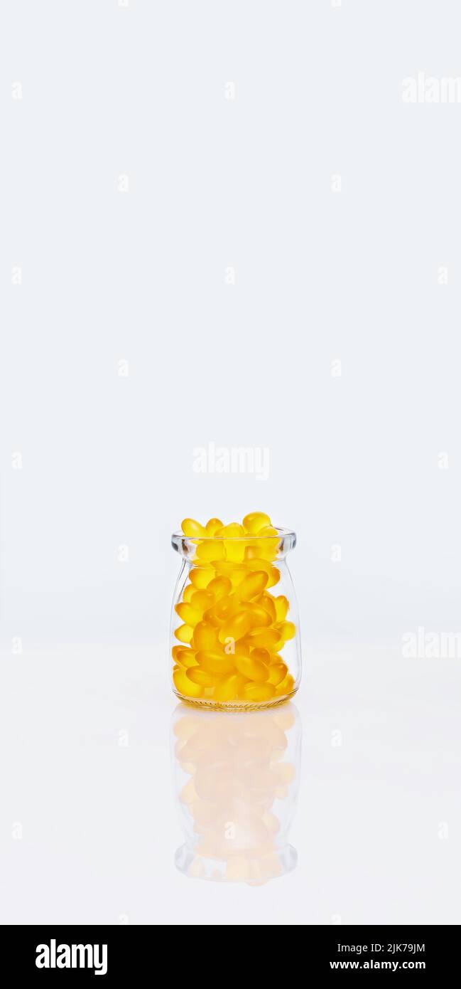 Fish oil. Gelatin capsules in a glass bottle on white table with copy