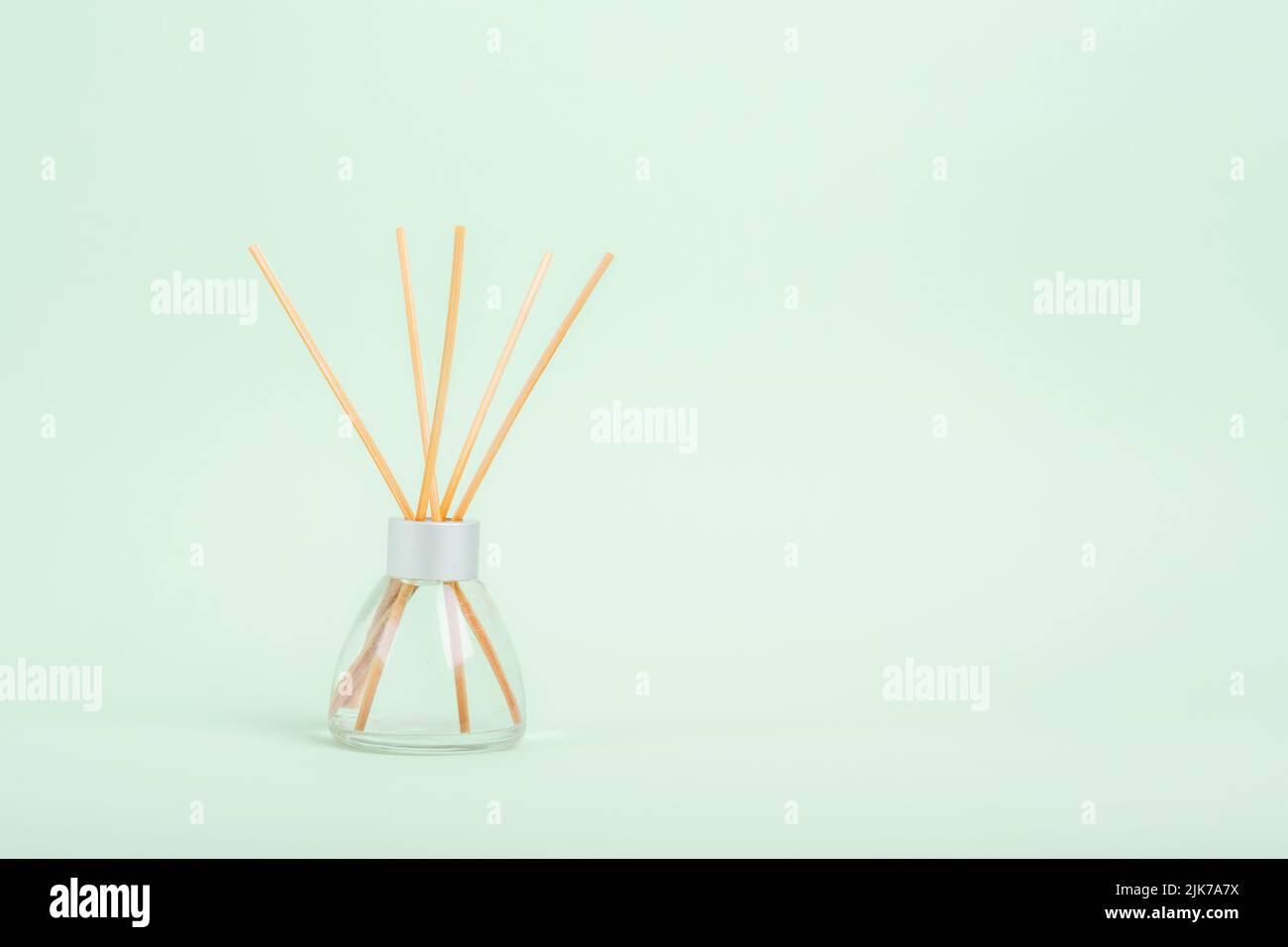 Aromatic Incense, oil diffuser with reed sticks on green background. Closeup, copy space. Stock Photo