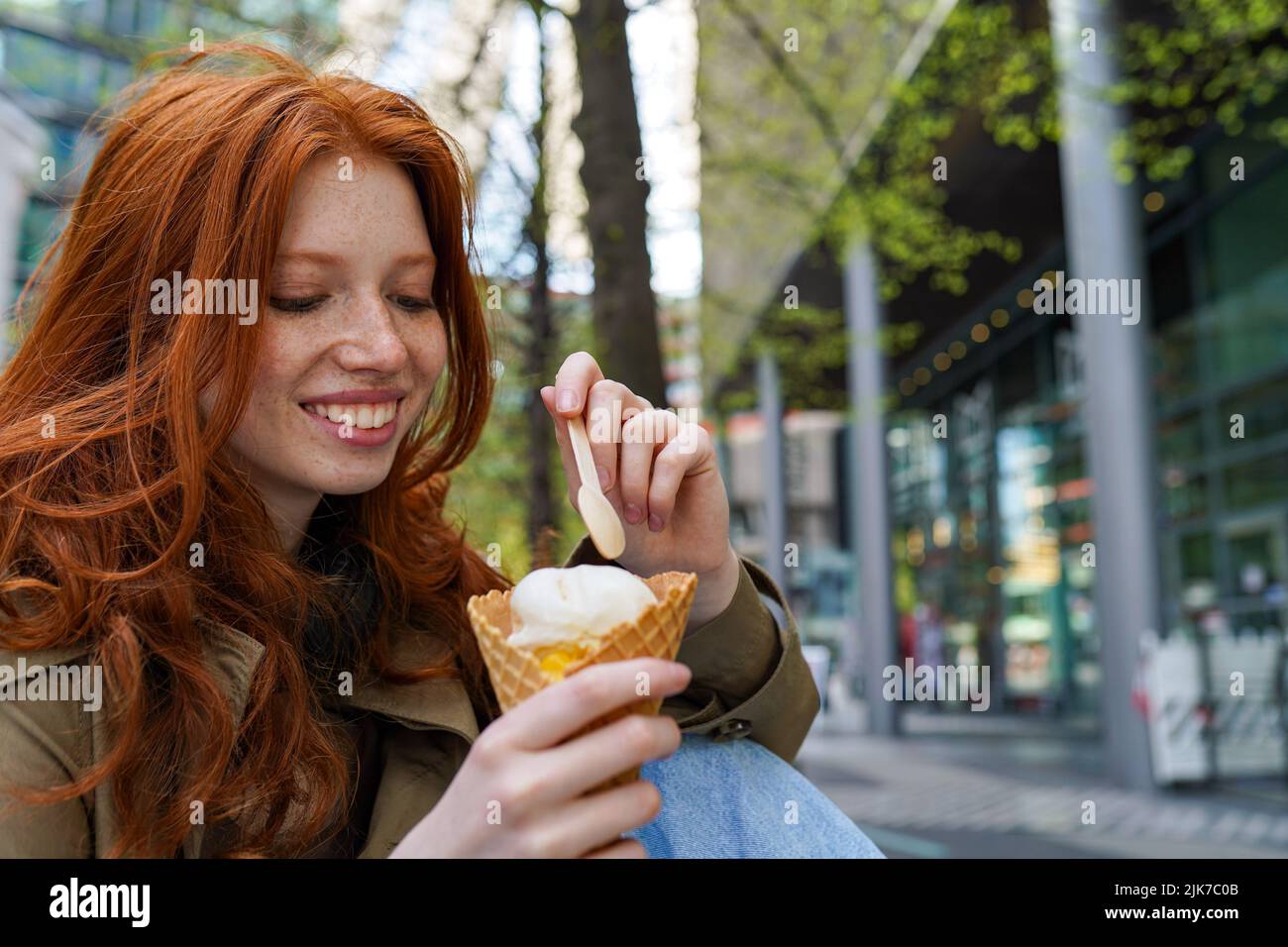 Smiling cool teen hipster girl eating ice cream on big city urban street. Stock Photo