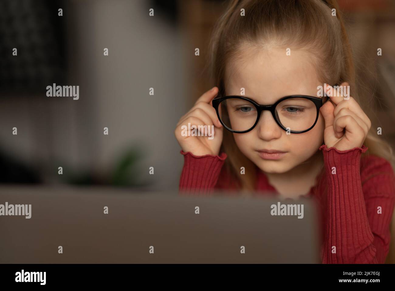 Kid Girl Squinting Eyes Wearing Glasses Looking At Laptop Indoors Stock