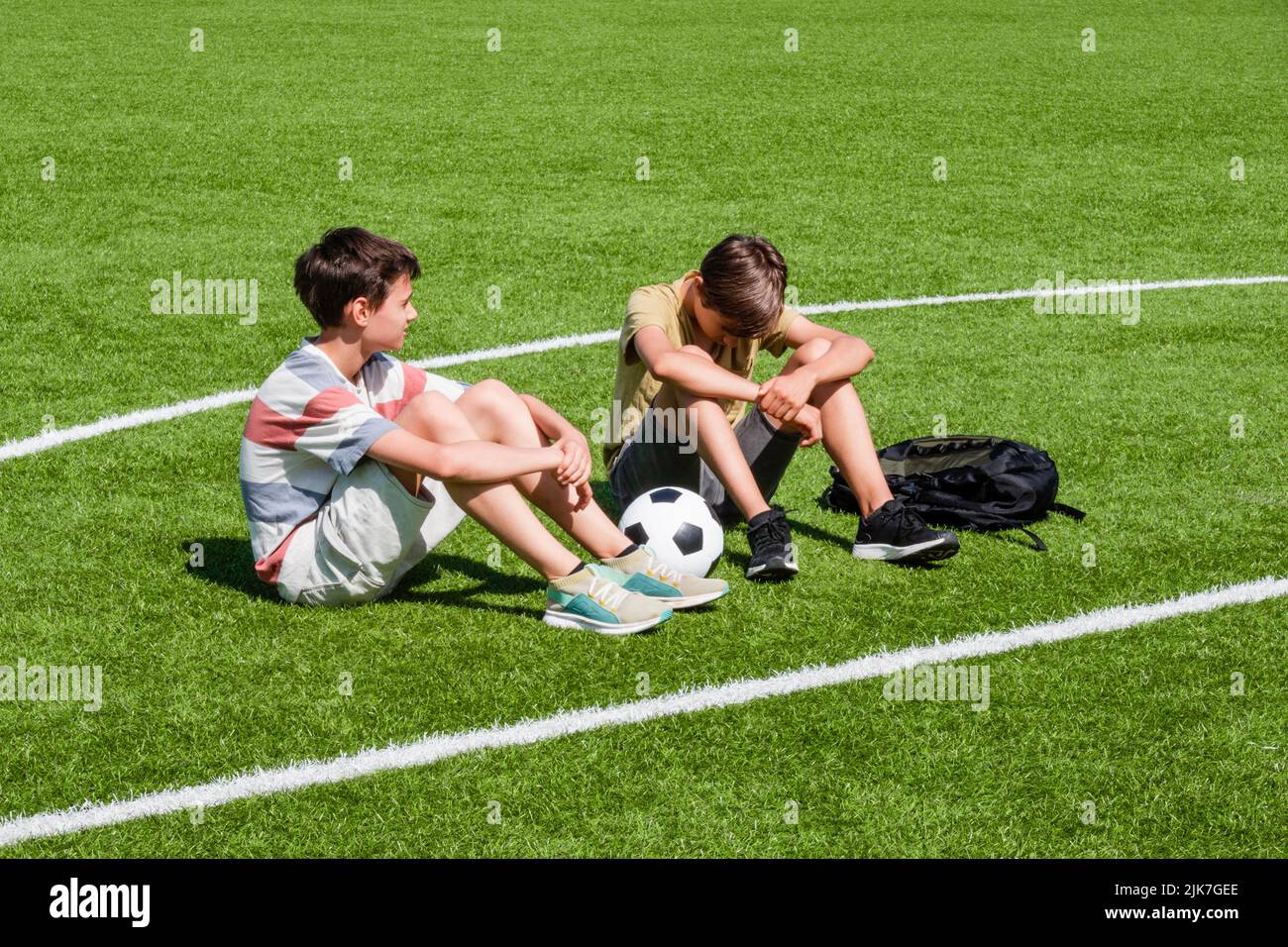 Teenage boy comforting consoling upset sad friend in school stadium. Education, bullying, conflict, social relations, problems at school, learning Stock Photo
