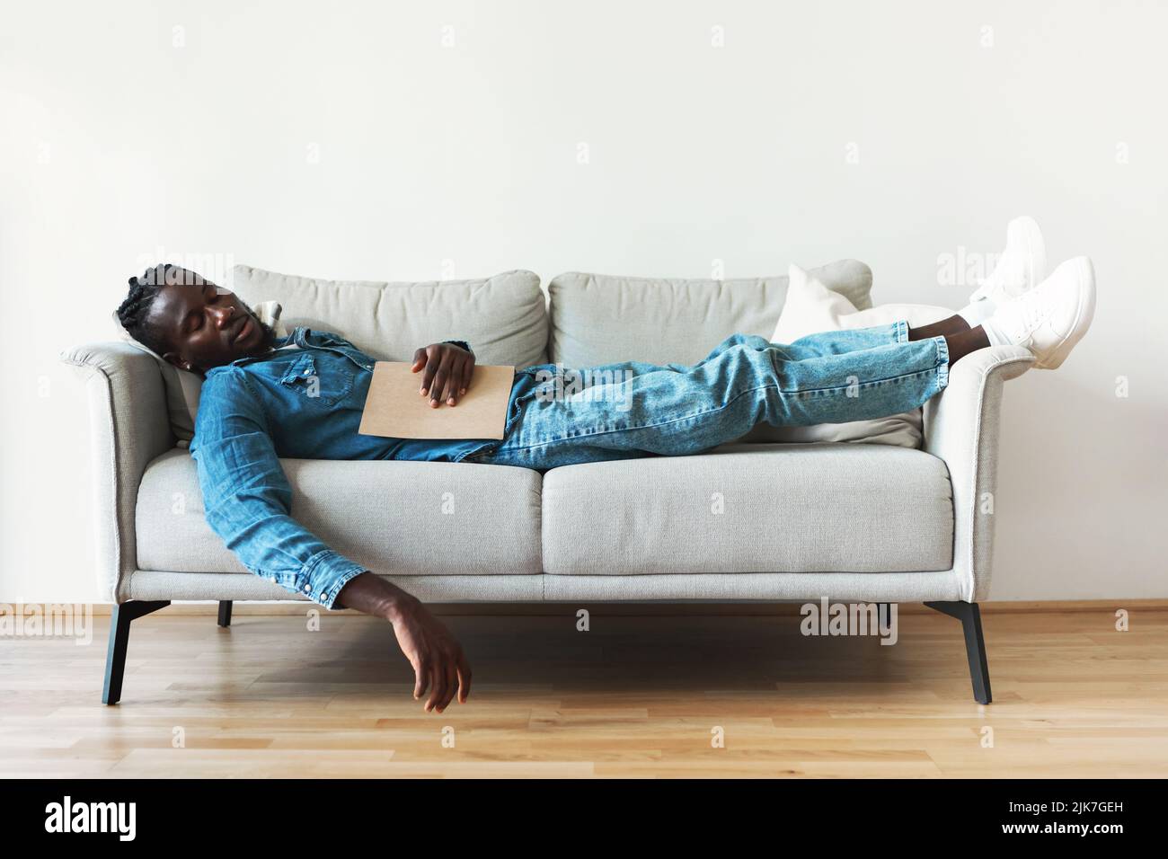 African Guy Sleeping Holding Book Resting Lying On Couch Indoor Stock