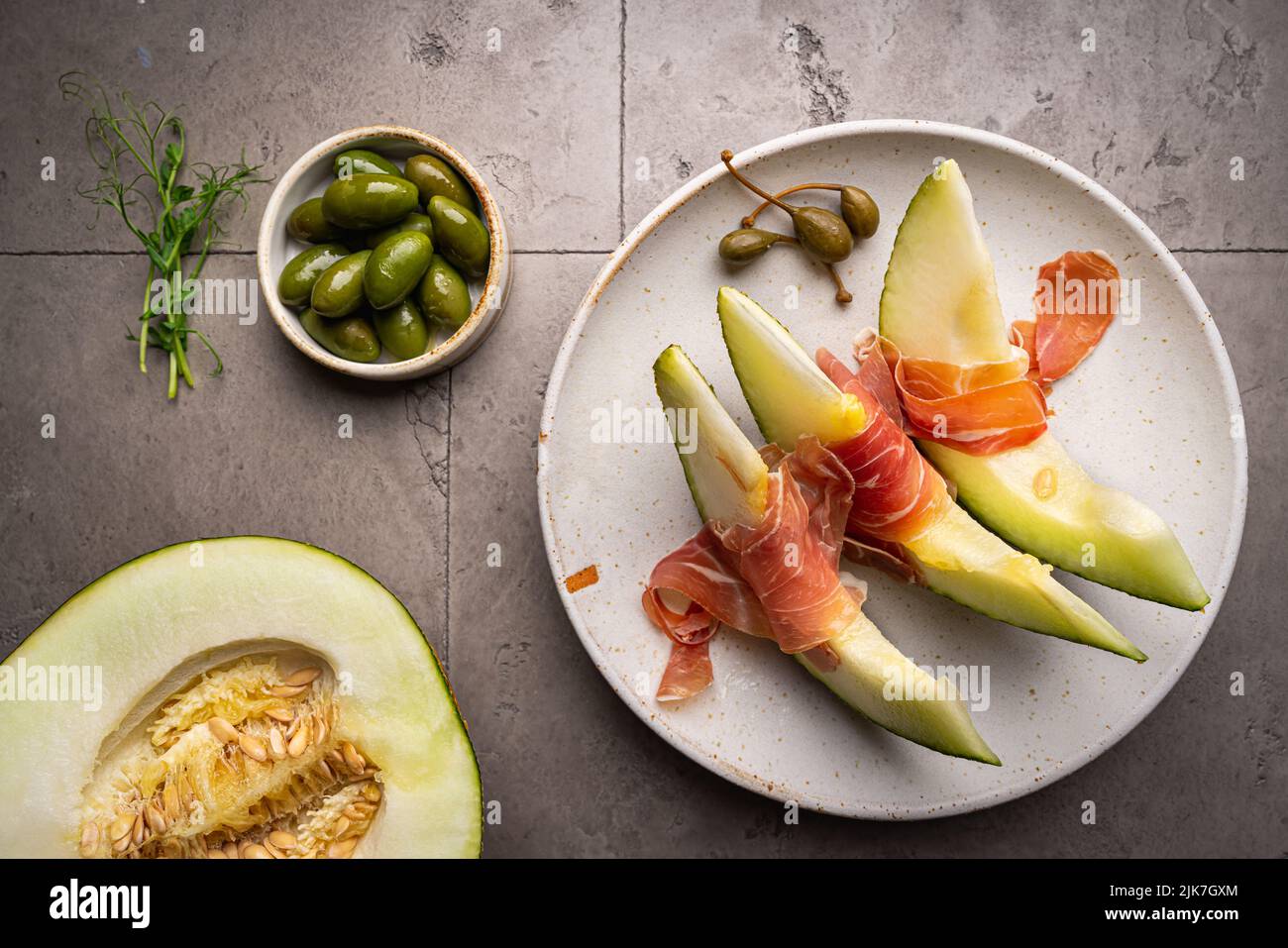 Jamon serrano, ham or prosciutto with melon and olives, a traditional