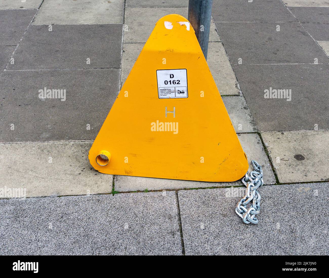 A car clamp obviously cut off a car and left on the footpath, Stock Photo