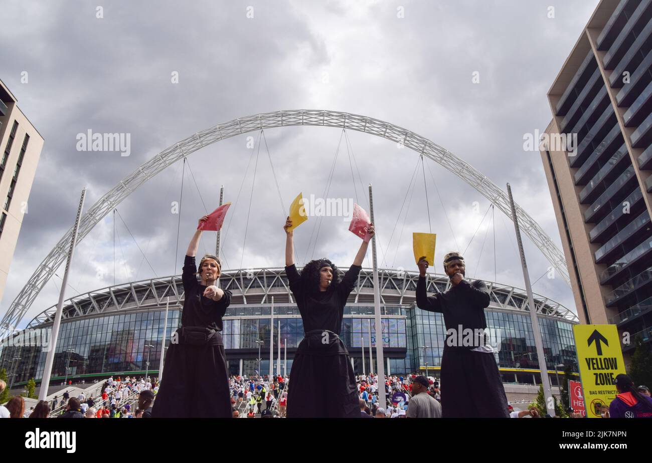 London, UK. 31st July, 2022. Performers wearing 'Referee' costumes stand on stilts while holding huge red and yellow cards outside Wembley Stadium ahead of the UEFA Women's Euro football final match, with England playing against Germany. Credit: SOPA Images Limited/Alamy Live News Stock Photo