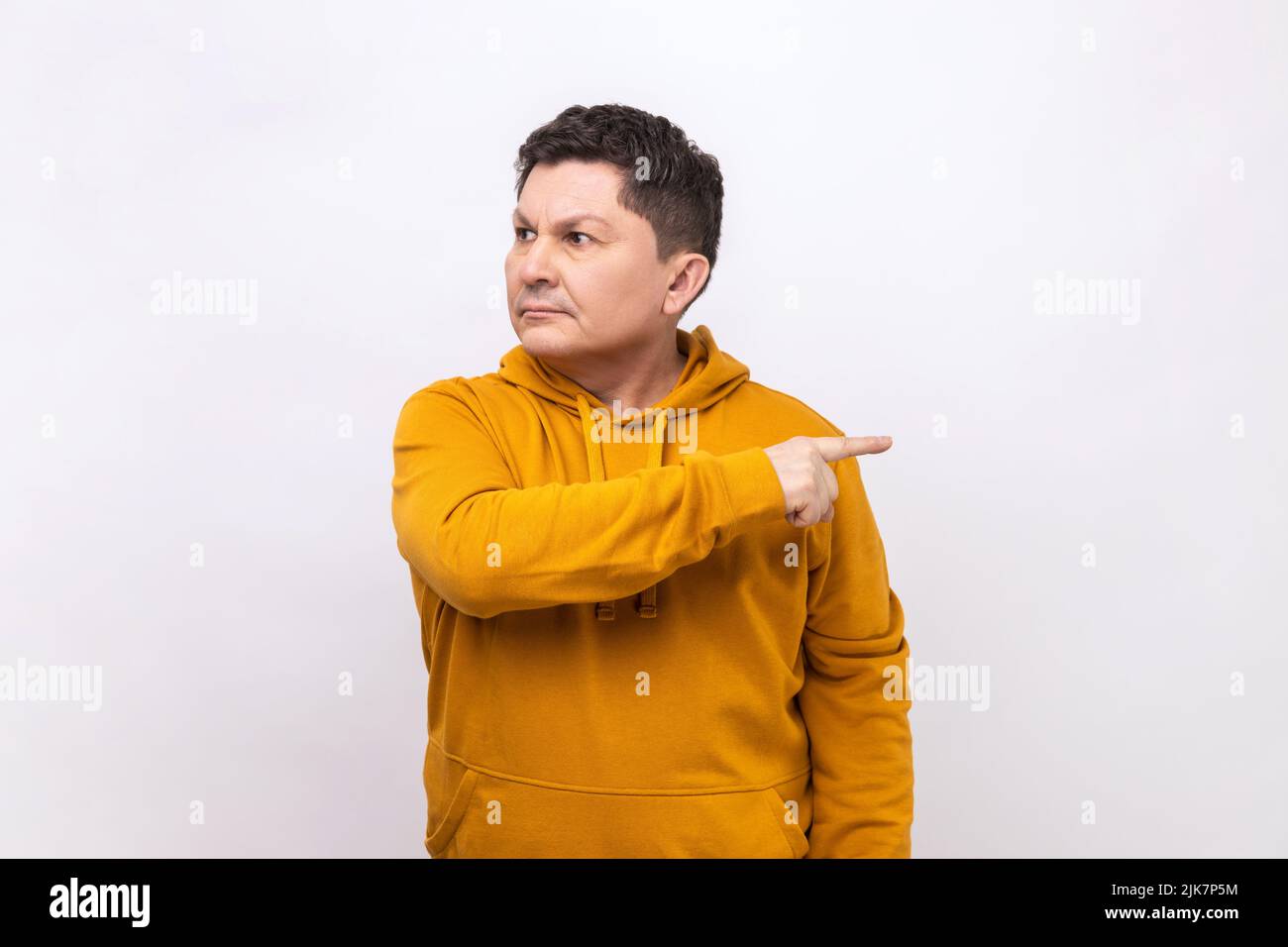 Leave me. Upset vexed man pointing finger aside, ordering get out and looking resentful, boss dismissing from work, wearing urban style hoodie. Indoor studio shot isolated on white background. Stock Photo