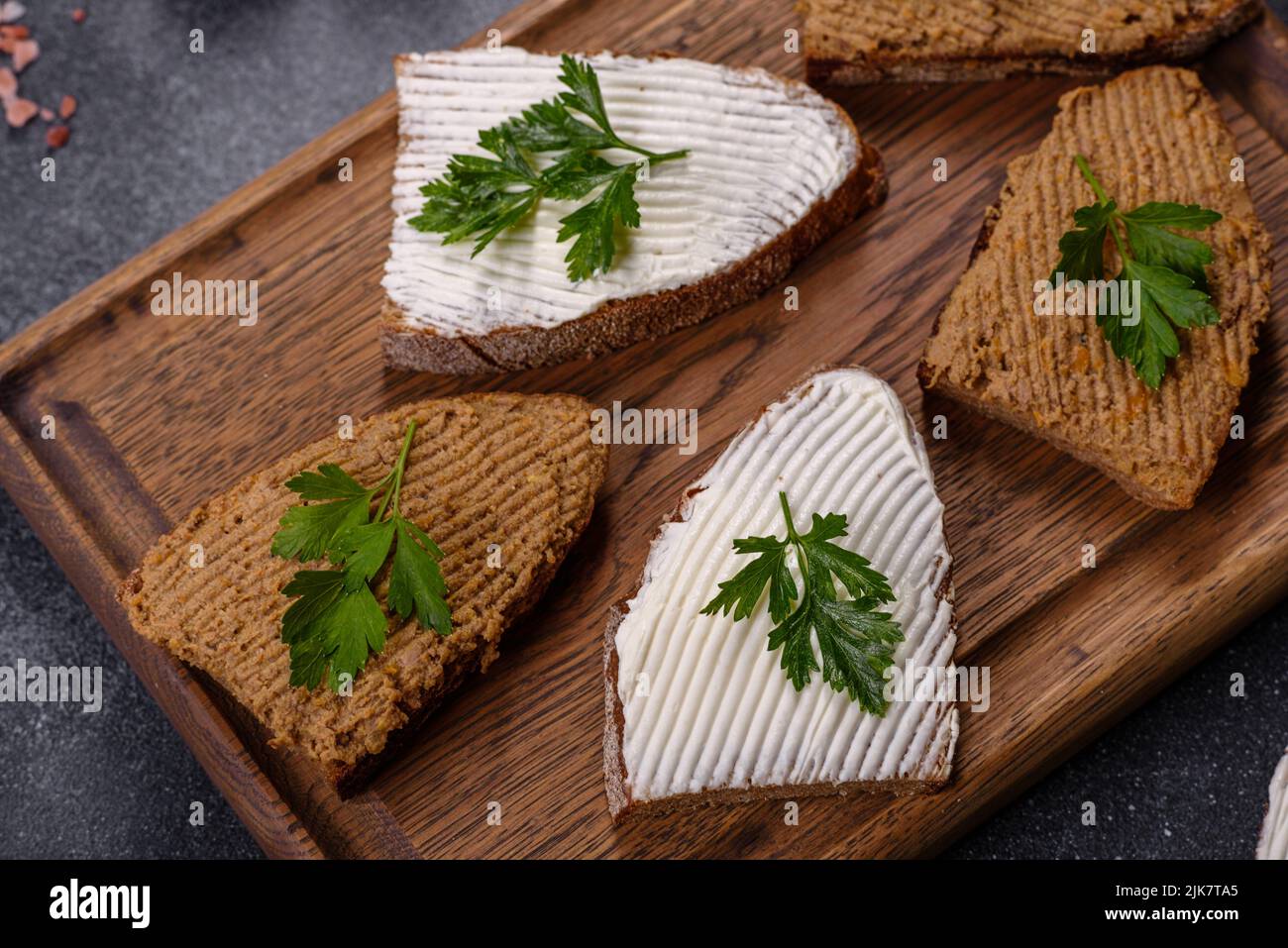 Fresh homemade chicken liver pate on bread over grey background Stock