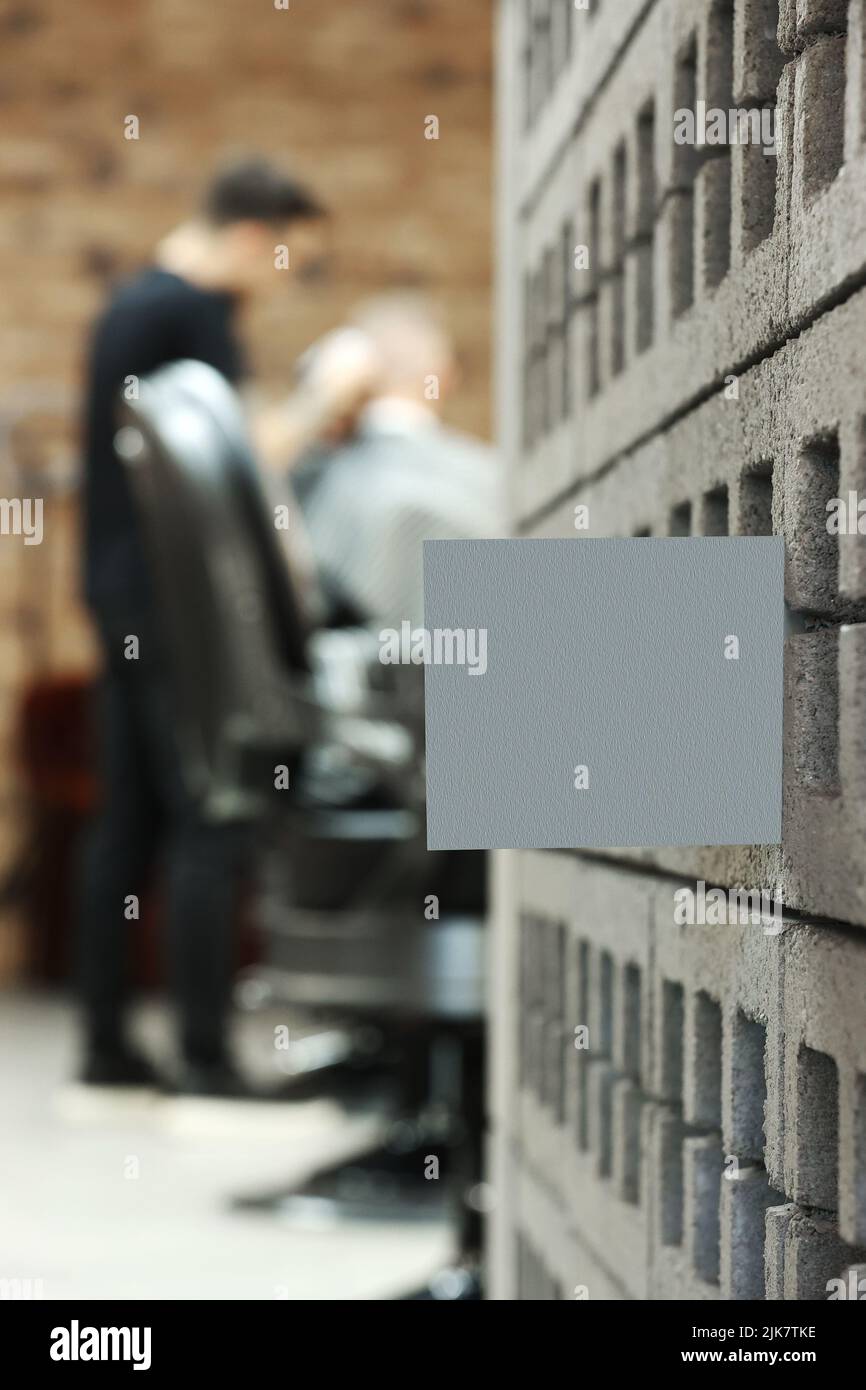 grey postcard or bossiness card with mock up on stylish barbershop or beauty salon background. blurred barber man is cutting and shaving the beard o c Stock Photo