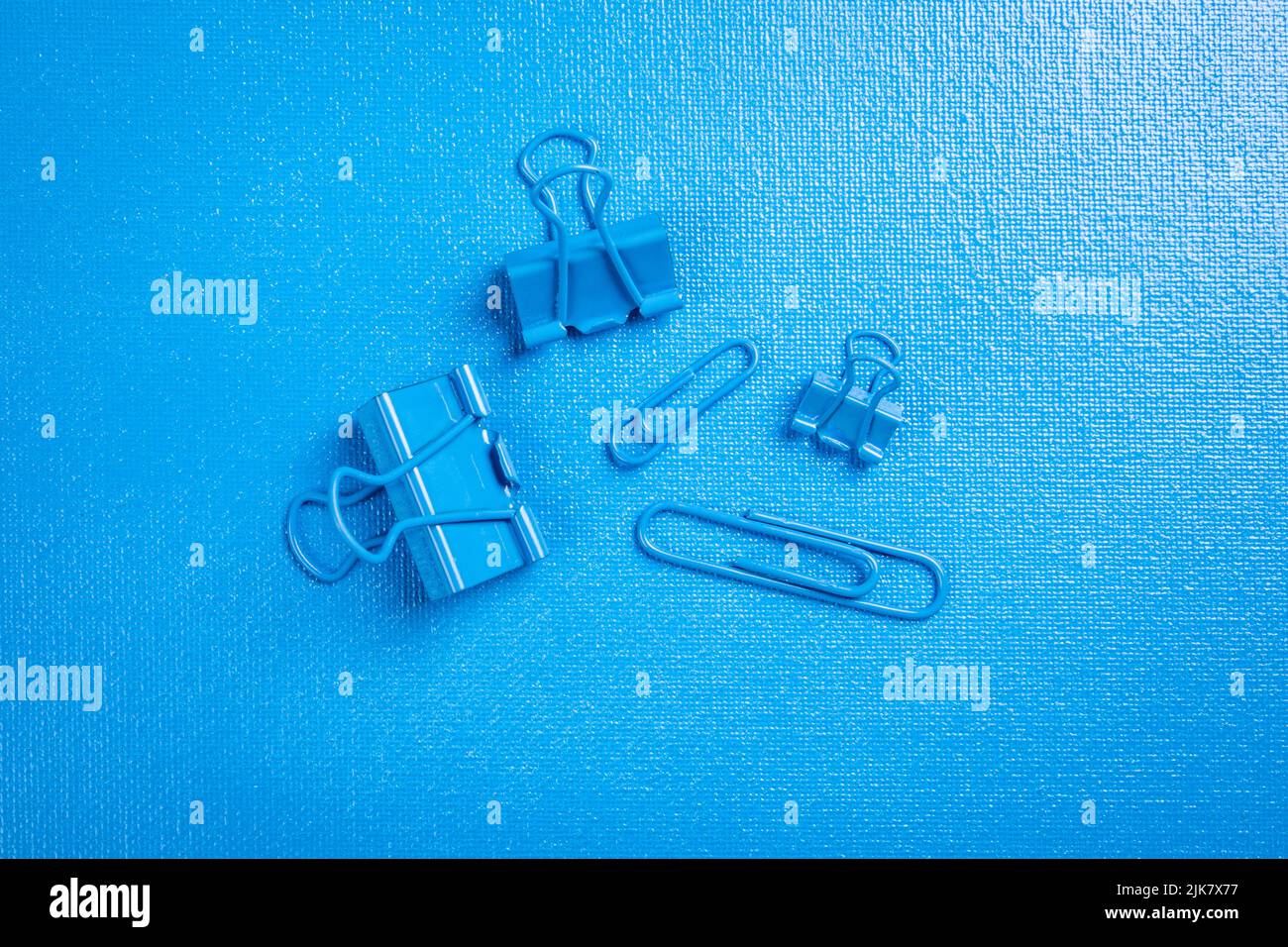 Paper clips and binder clips on a blue textured background. Stock Photo