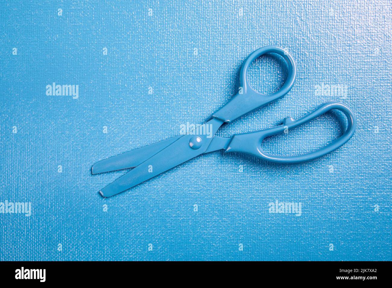 Scissors for cutting paper, hair and textiles. Stationery, blue texture