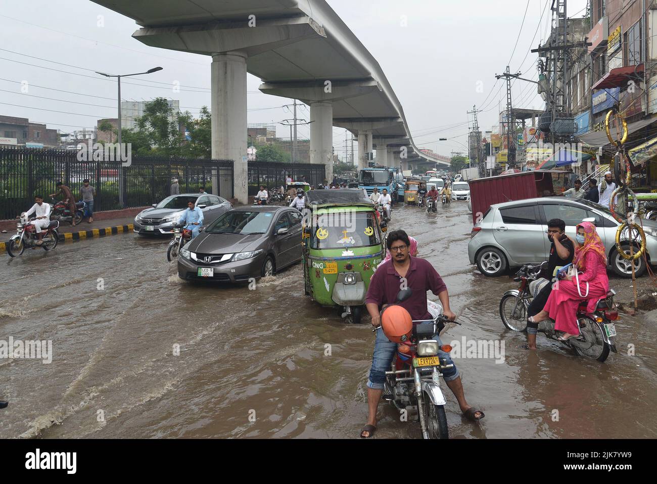 Lahore, Pakistan. 29th July, 2022. Pakistani people wade through a flooded road with difficulty after heavy rainfall in Lahore, Pakistan, on July 29, 2022. The latest spell of monsoon rain has broken a 20-year record as the provincial capital received 234mm of downfall in seven hours. (Photo by Rana Sajid Hussain/Pacific Press/Sipa USA) Credit: Sipa USA/Alamy Live News Stock Photo