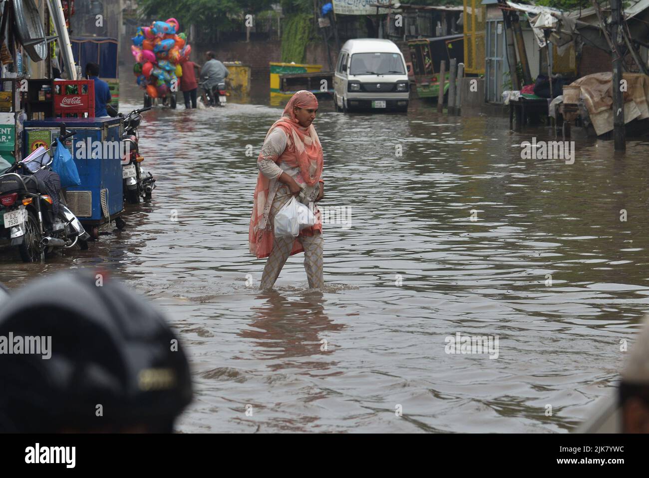 Lahore, Pakistan. 29th July, 2022. Pakistani people wade through a flooded road with difficulty after heavy rainfall in Lahore, Pakistan, on July 29, 2022. The latest spell of monsoon rain has broken a 20-year record as the provincial capital received 234mm of downfall in seven hours. (Photo by Rana Sajid Hussain/Pacific Press/Sipa USA) Credit: Sipa USA/Alamy Live News Stock Photo