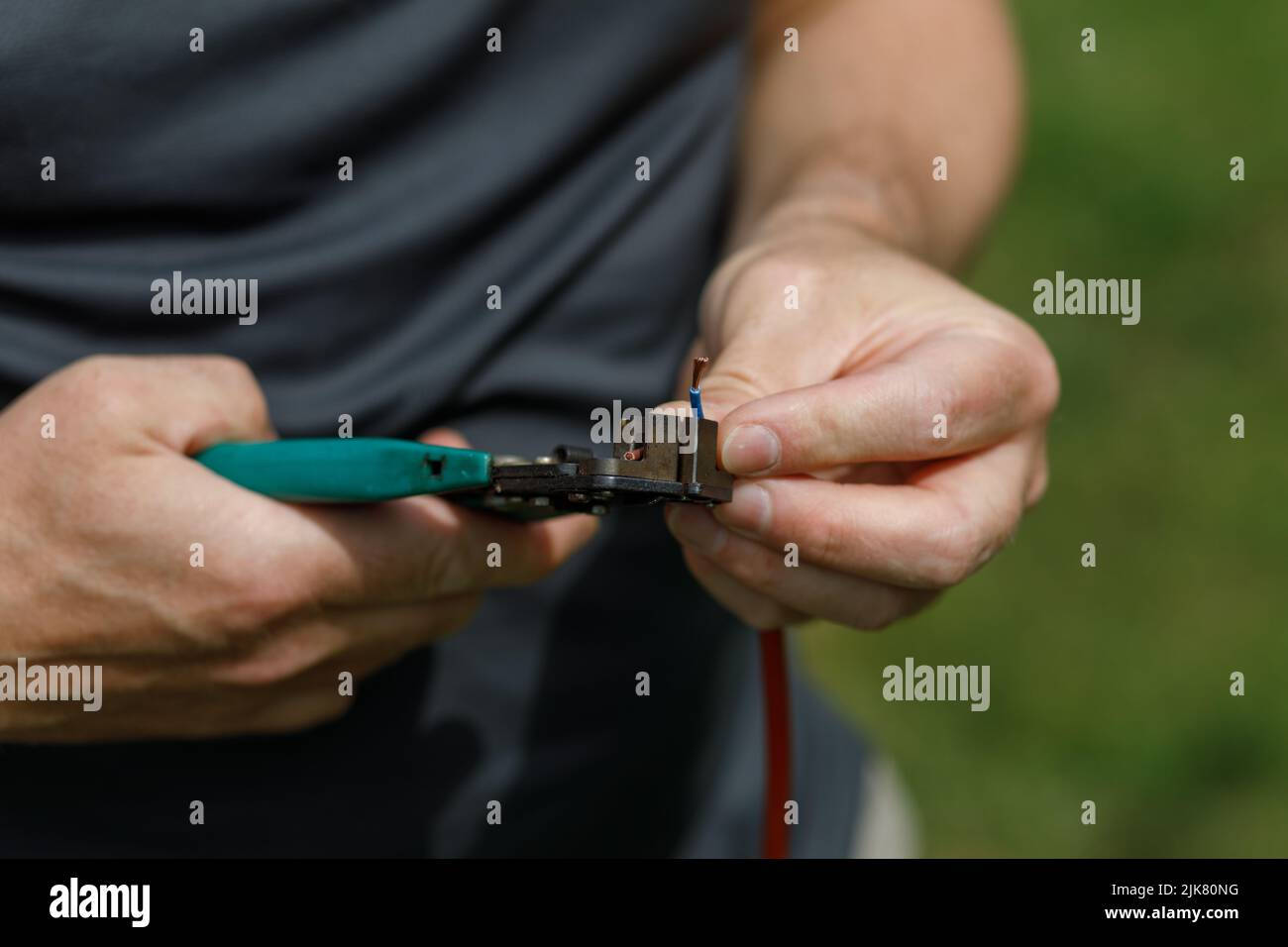 Cutting electrical wires with a wire cutter, held in a mans hands Stock