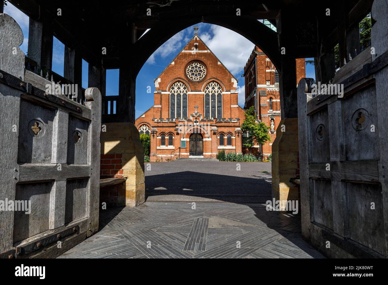 The west entrance to an English Victorian red brick church, seen through wooden Lych gates Stock Photo