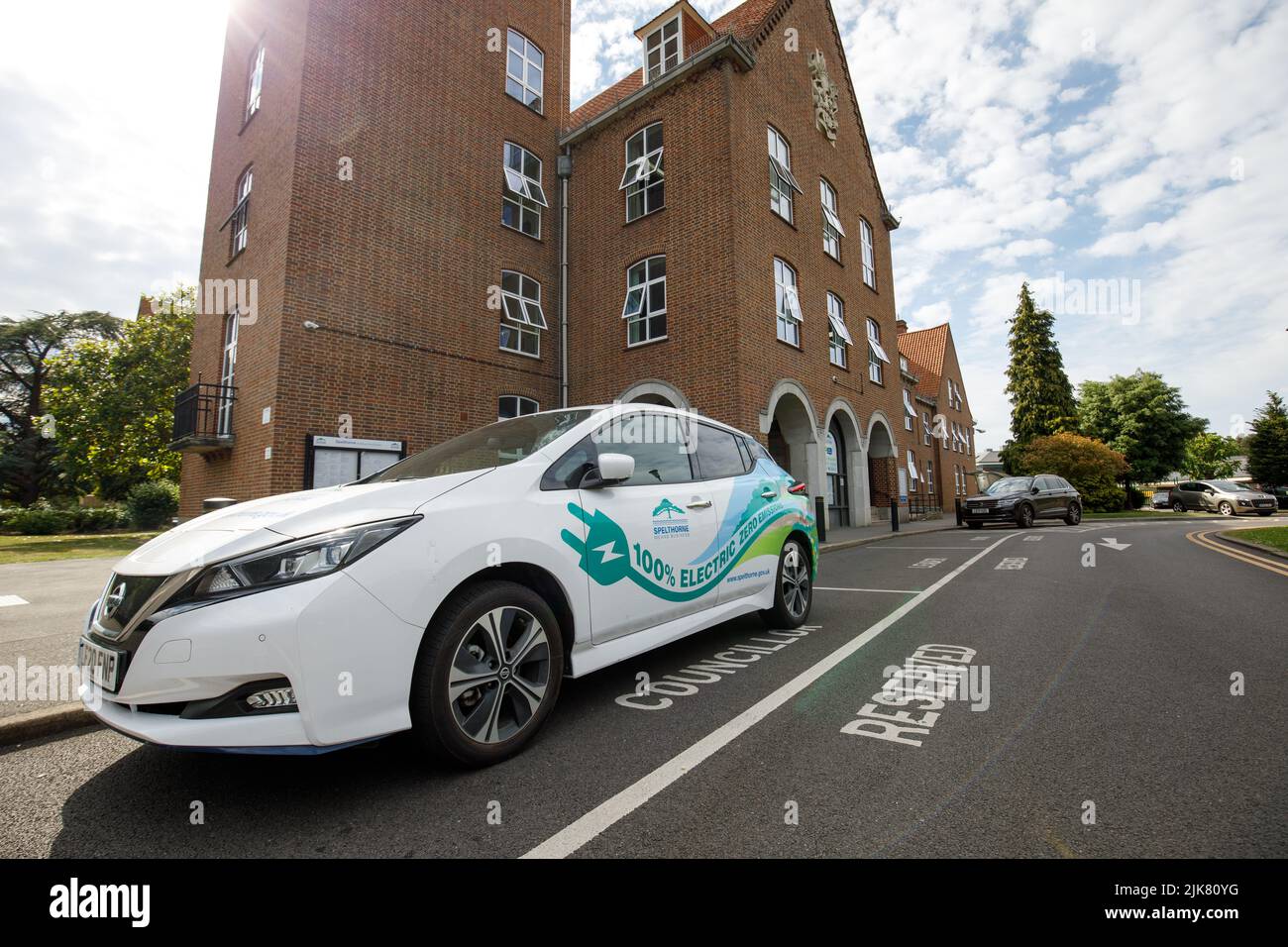 An electric car with promotional advertising graphics, used by a councillor from the Borough of Spelthorne, outside the council offices in Staines Stock Photo