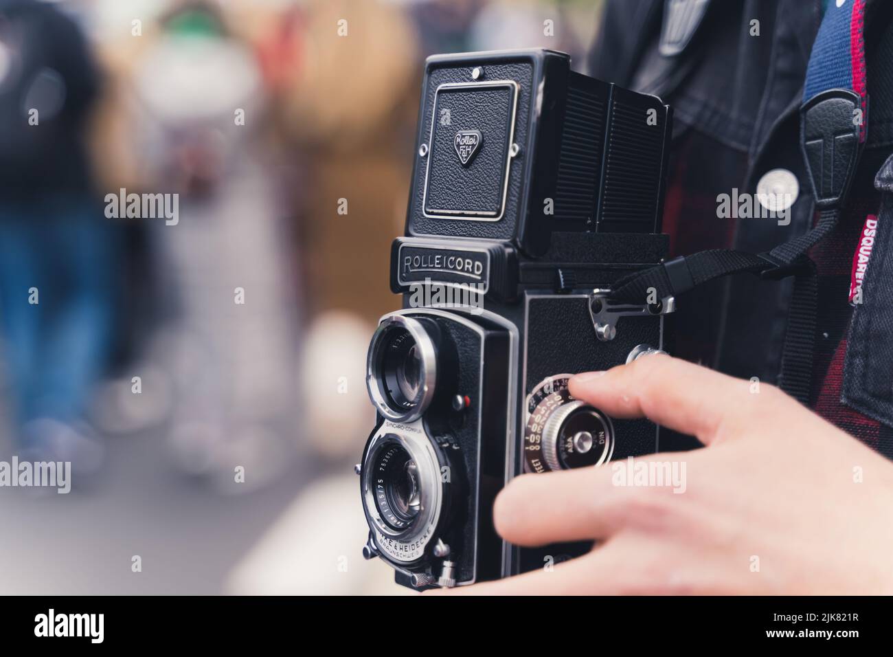 05.28.2022 Warsaw, Poland. Black old-fashioned analog medium format camera held by an unrecognizable caucasian person. Closeup outdoor shot with blurred background. High quality photo Stock Photo