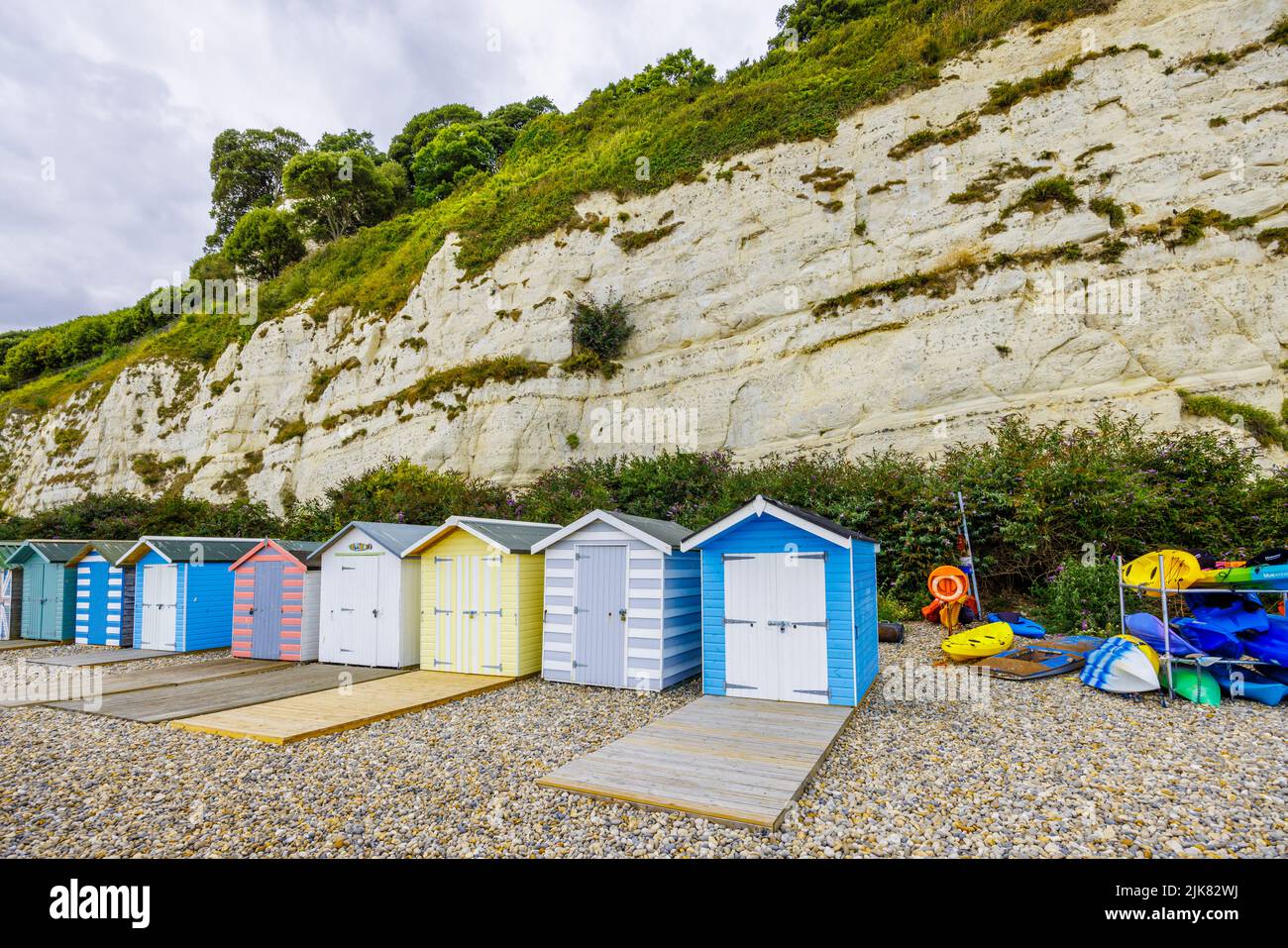 A row of beach huts at the foot of chalk cliffs at Beer, a small coastal village on Lyme Bay in the Jurassic Coast of East Dorset, south-west England Stock Photo