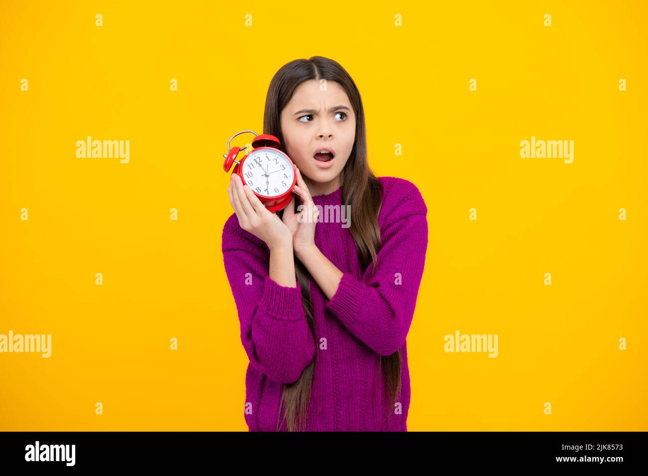 Teen girl 12, 13, 14 years old look at alarm clock. Time for shopping sales. Good morning, checking time. Angry teenager girl, upset and unhappy negat Stock Photo