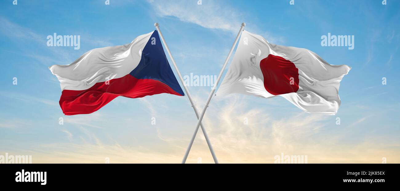 two crossed flags japan and Czech republic waving in wind at cloudy sky ...