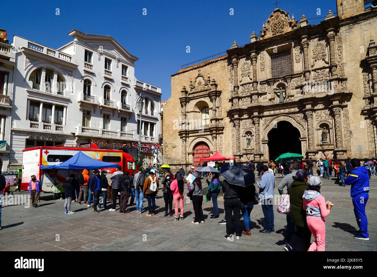 La Paz, Bolivia. 31st July 2022. People queue outside a mobile health clinic offering free health and dental checks / consultations organised by the La Paz city authorities in Plaza San Francisco in the city centre. Behind is San Francisco church, the most important and impressive colonial church in the city. Stock Photo