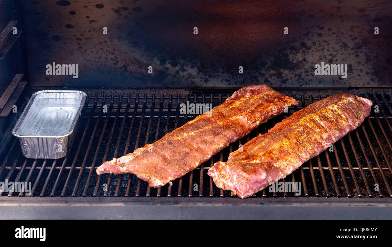 Golden pork ribs on a smoker with a water tin Stock Photo
