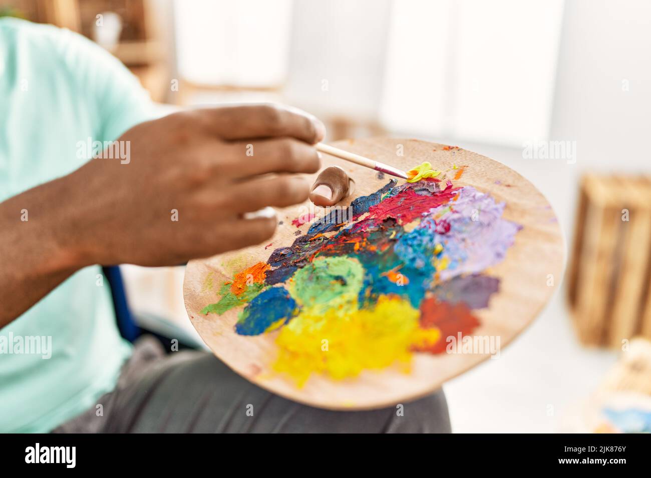 Hand of african american artist man mixing color on palette at art studio. Stock Photo