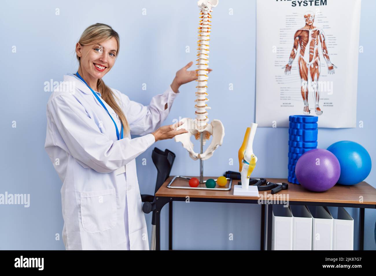 Young blonde woman wearing physiotherpist uniform pointing to