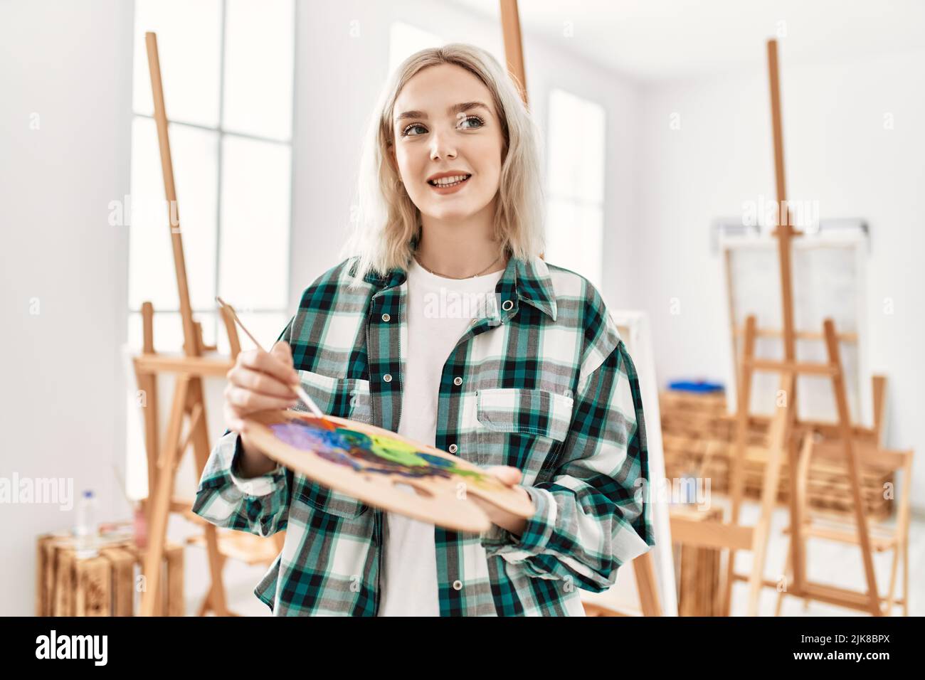 Young artist student girl smiling happy holding paintbrush and palette ...