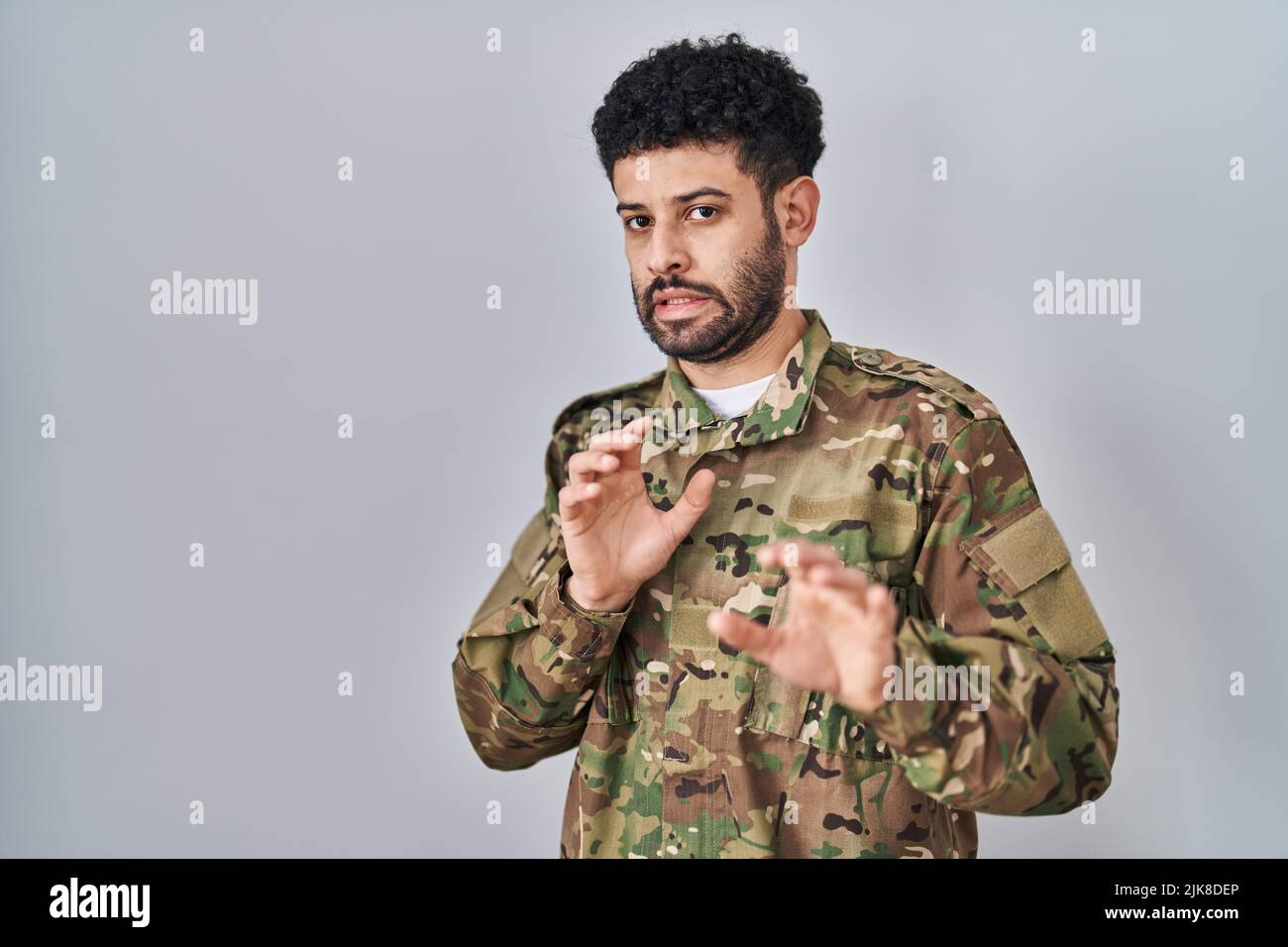Arab man wearing camouflage army uniform disgusted expression