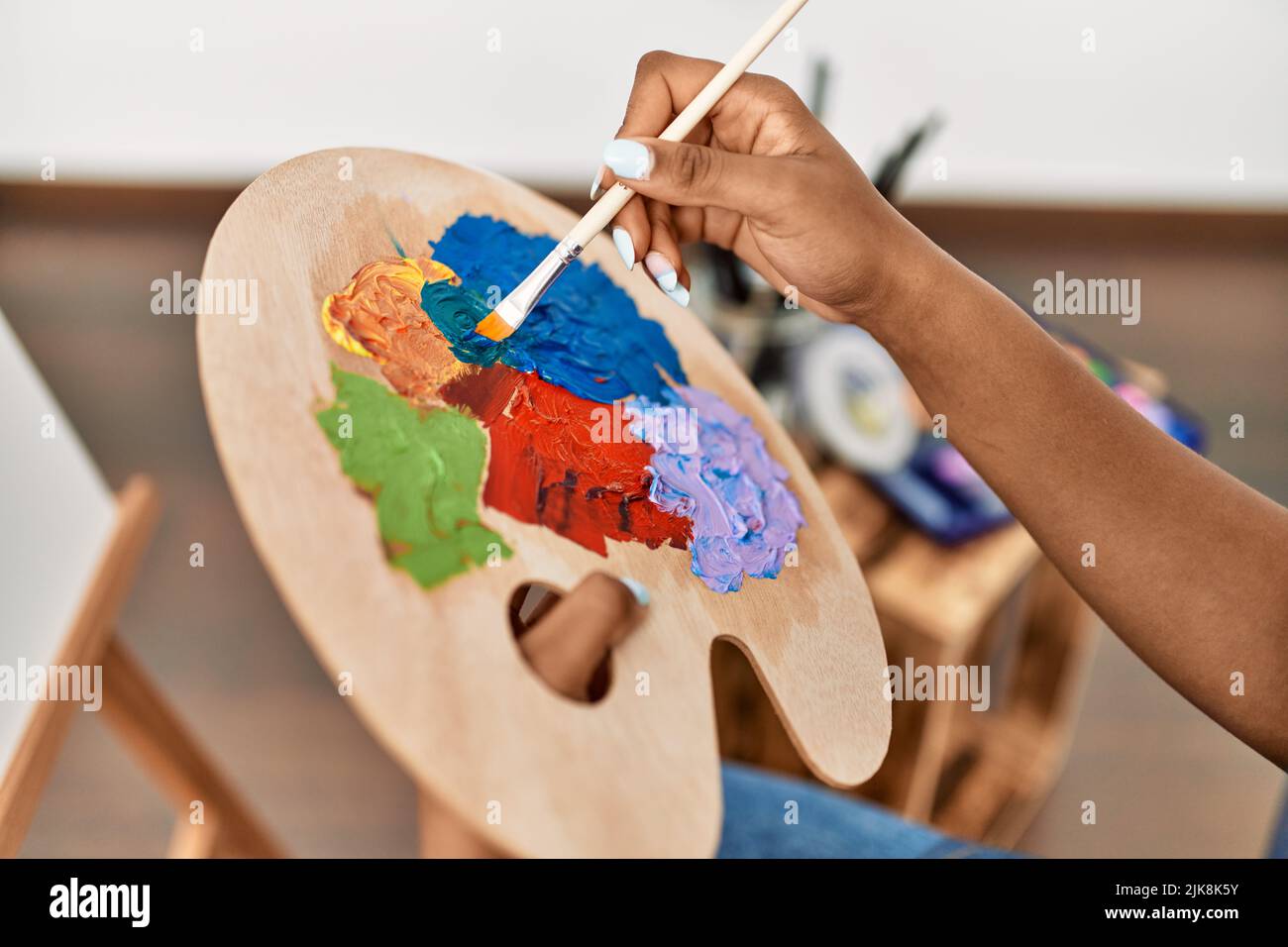 Young african american woman mixing color on palette at art studio Stock Photo