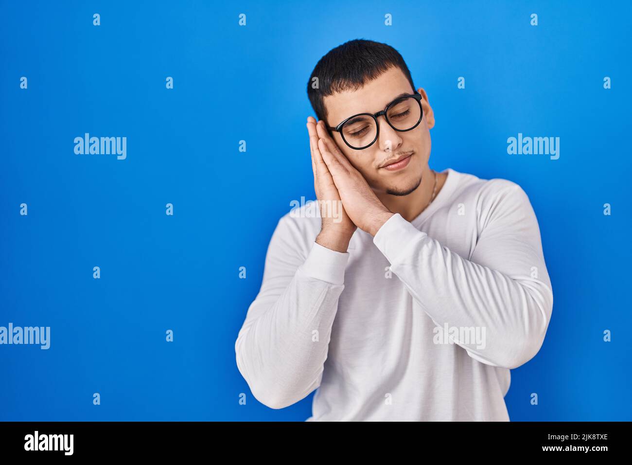 Young arab man wearing casual white shirt and glasses sleeping tired ...
