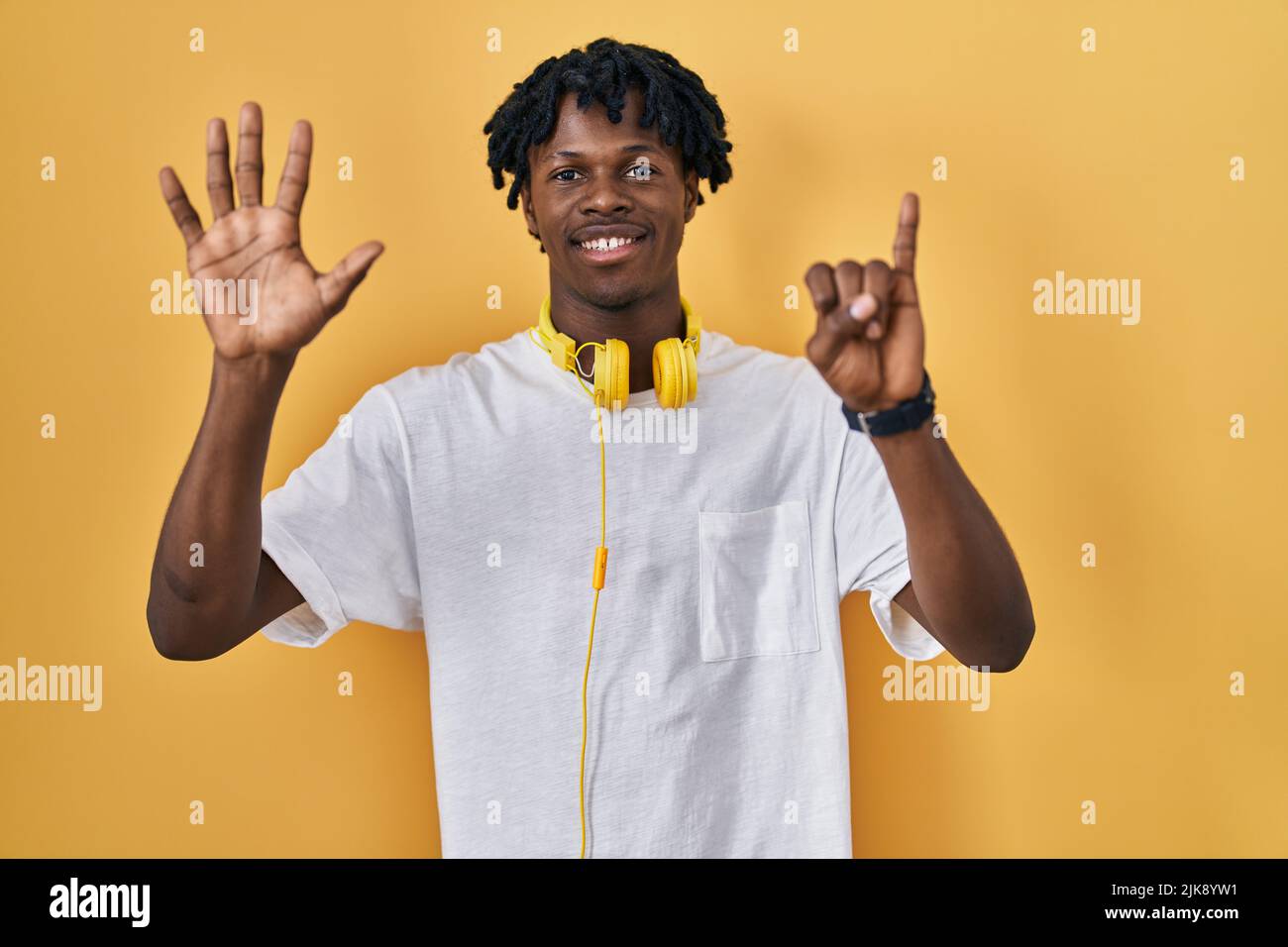 Young african man with dreadlocks standing over yellow background