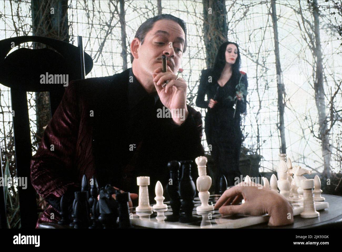 Raul Julia, Anjelica Huston & Thing Film: The Addams Family (1991) Characters: Gomez Addams, Morticia Addams  Director: Barry Sonnenfeld 22 November 1991   **WARNING** This Photograph is for editorial use only and is the copyright of PARAMOUNT and/or the Photographer assigned by the Film or Production Company and can only be reproduced by publications in conjunction with the promotion of the above Film. A Mandatory Credit To PARAMOUNT is required. The Photographer should also be credited when known. No commercial use can be granted without written authority from the Film Company. Stock Photo