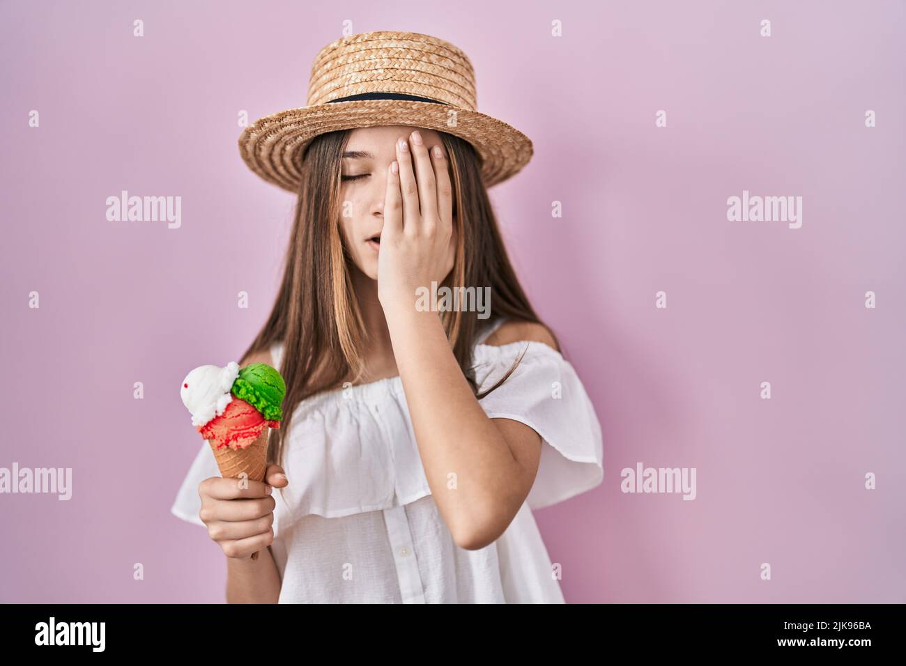 Teenager girl holding ice cream yawning tired covering half face, eye