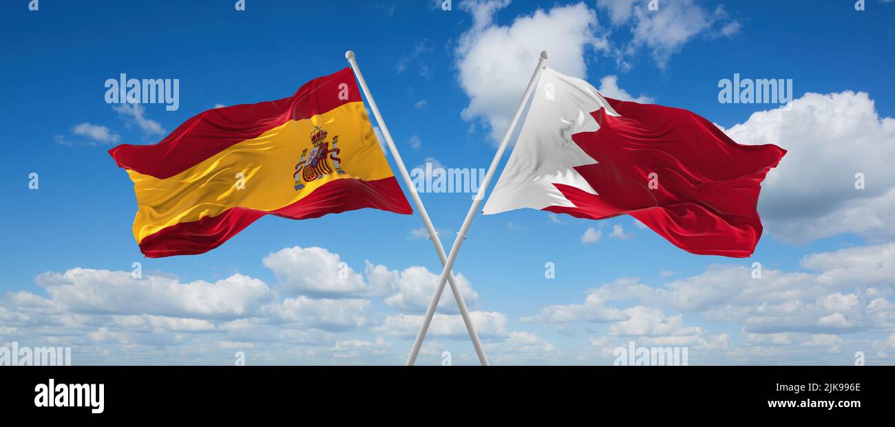 two crossed flags Bahrain and spain waving in wind at cloudy sky ...