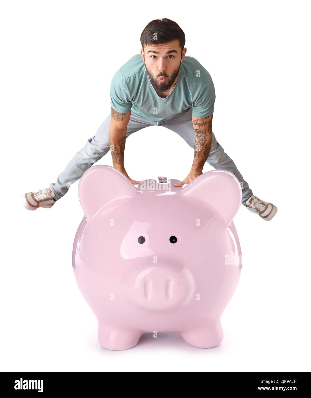 Cool tattooed young man and big piggy bank on white background Stock ...