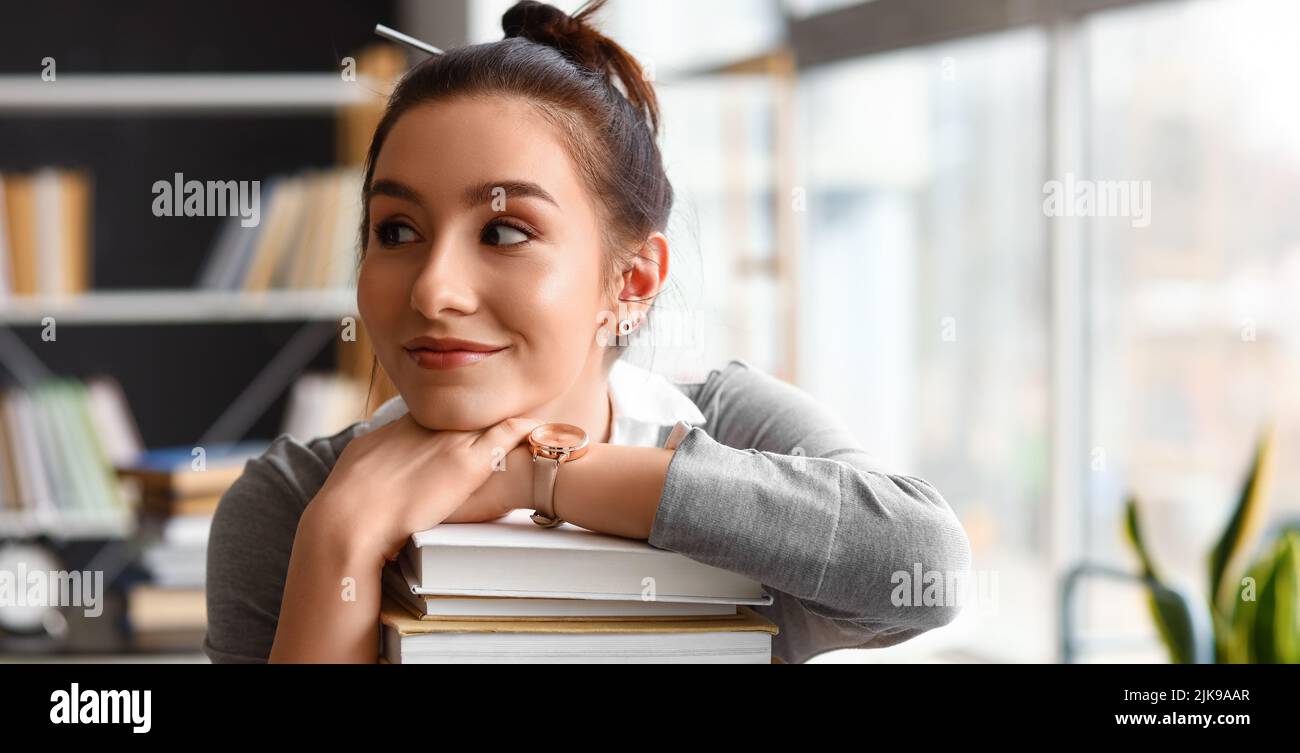 Beautiful female student with stack of books in library Stock Photo - Alamy